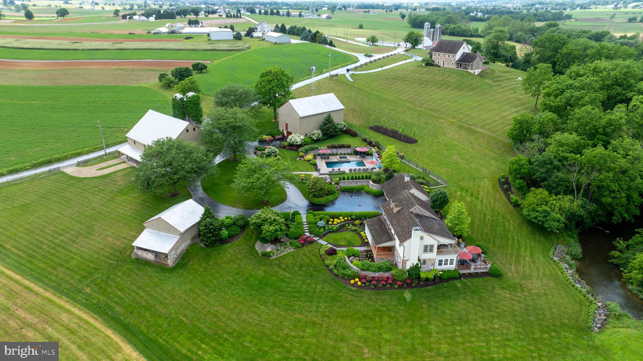 Experience the charm of this enchanting 1800’s farmhouse nestled in East Earl. A standout feature of this property is its transformed barn, now a captivating Party Barn  with an Old English Pub ambiance. Ideal for car collectors, the residence offers twelve indoor car storage spaces along with ample outdoor parking. Nestled against the serene backdrop of the Conestoga River, it also has an inviting inground heated pool with a hot tub. Upon entering, you're welcomed by a sunlit sunroom with heated floors, leading seamlessly to a fully equipped kitchen. This culinary haven features Premier cabinets, a Thermador refrigerator, a dual-door Perlick beverage fridge, a Viking gas four-burner range, and more. Hardwood floors and a gas fireplace grace the inviting living room, perfect for warm winter nights. The family room has heated tile floors, a convenient built-in desk, and access to the patio, designed for enjoying summer days. Outdoors, the patio features a built-in Lynx gas grill, refrigerator, and side burner. The second floor features three bedrooms, including the primary, while the third floor presents a spacious fourth bedroom. The primary bedroom is a sanctuary, complete with an ensuite bathroom featuring heated marble floors, double sinks, a spacious walk-in closet with ample shelving enclosed by charming barn doors, and a balcony for a breath of fresh air. The inground pool area offers a private oasis for soaking up the summer sun, complete with its own fenced area and rejuvenating hot tub. Adjacent to the pool, the transformed Party Barn beckons with its Old English Pub allure, showcasing a well-appointed bar area with a refrigerator, ice maker, dishwasher, and draft beer dispenser, alongside a comfortable sitting area. For car enthusiasts, the adjacent car storage area provides ample space for six vehicles, fulfilling every collector's dream. Don't miss out on the opportunity to call this remarkable property home—schedule your showing today!