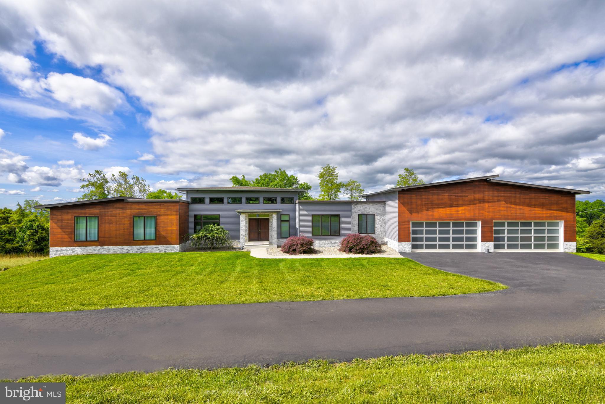 Nestled high on the outskirts of Leesburg, providing must see views, while just a 2 mile stroll from downtown, this stunning like new 4 bedroom, 3.5 bath home is a true masterpiece. Crafted with meticulous attention to detail, it boasts countless designer finishes and top-of-the-line upgrades throughout.

The exterior showcases Tigerwood and Hardie Plank siding, complementing the car enthusiast’s dream garage—an oversized 4 car space complete with a hydraulic lift, providing room for up to 8 vehicles. Additionally, there’s a convenient single garage/shed accessible from the backyard.

Inside, the open floor plan features 9 foot ceilings in the kitchen and soaring 14 foot ceilings in the great room. Quartz countertops, accentuated by under-cabinet lighting grace the kitchen, while bamboo wood floors add warmth to the main level. Recessed and chic designer lighting sets the mood, while an indoor/outdoor gas fireplace and wired surround sound options enhance your entertainment experience.

Enjoy the morning sun on the front porch or catch breathtaking sunsets on your private elevated deck, complete with a louvered pergola, fire table, and TV hookup. For relaxation, the lower patio features a hot tub and an outdoor TV. The abundance of windows floods the home with natural light.

The luxurious owner’s suite and perfectly designed baths add to the appeal, and the finished lower level boasts a movie quality theater room with a 133" screen and projector. These exceptional features make this home truly special. Step inside and prepare to fall in love!

Other amenities on this one acre property include: NO HOA, EV charger, invisible pet fence, trailer/RV parking pad with a 50-amp outlet and water hookup.
