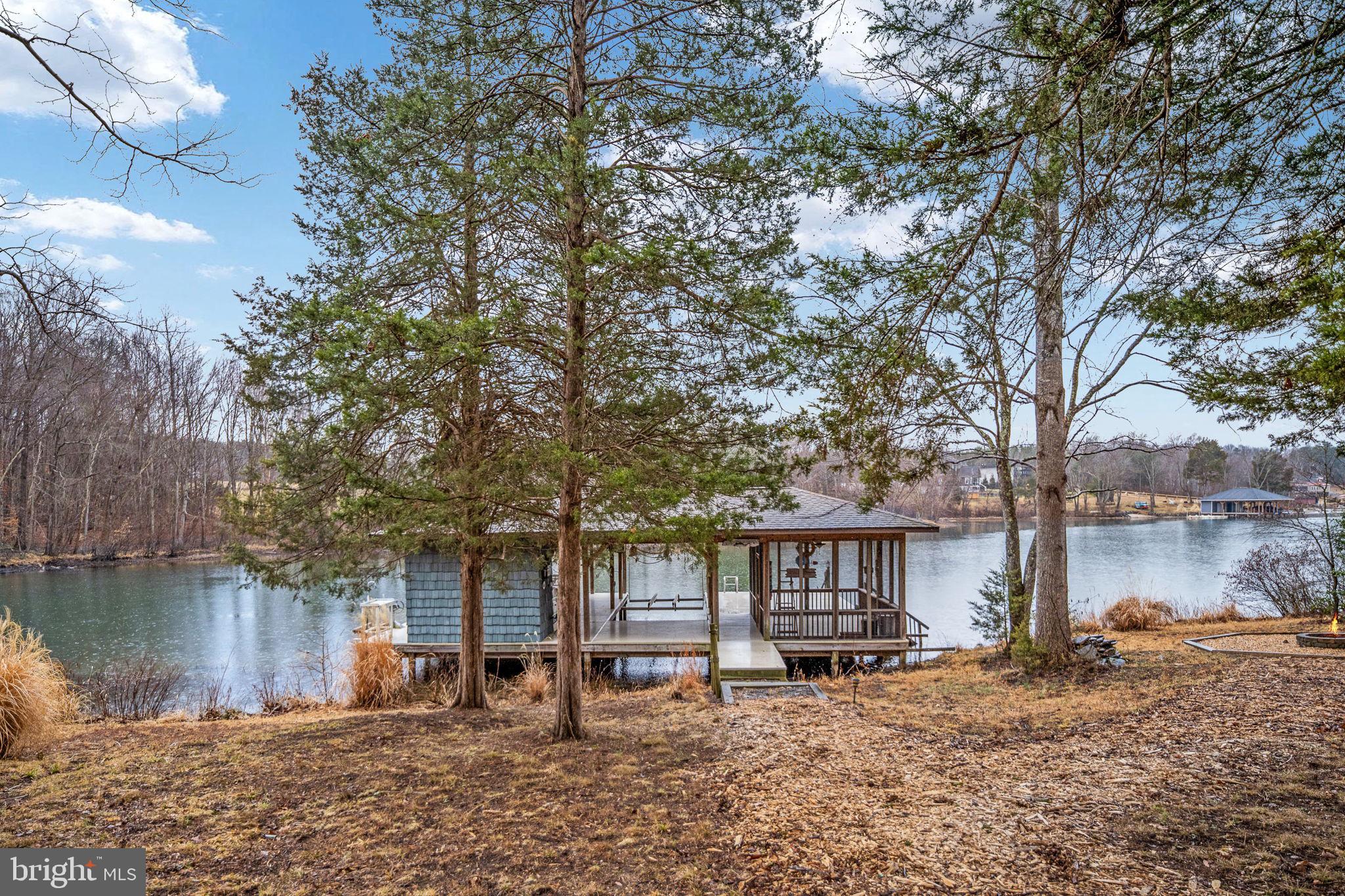 Welcome to 3900 Water Front Court on the Public (cold) Side of Lake anna.  Located in  the community of Sycamore Shoals.  

 Built in 2011, this beautiful custom home is located on a quiet cul-de-sac.  Over 4000 sq ft. across 3 levels

 Follow the driveway up and around the circular drive to arrive at the house.  Plenty of parking and easy and access to the garage.  A beautiful Cape Cod style house with a covered wrap around porch and a simi detached garage that joins the house by a covered walkway.  This home has wonderful flow from one room to the next for easy movement through the house.  

Home features 2x6 exterior wall construction,  high ceilings and lots of windows to let in the natural light.  A wall of windows facing the lake greet you when you enter the home.  A main level primary bedroom with ensuite has double vanities, a soaking tub, and a walk in shower.  Full bath on each level, 2 on the main level.  2 bedrooms and a bathroom on the upper level.   Kitchen has a gas stove and a double oven.  The laundry room is conveniently located next to the kitchen.   The home has 2 fireplaces.  One gas fireplace on the main level in the living room.  One wood burning fireplace on the lower level in the family room.  Living room, den/guest room, dining room, eat in kitchen on the main level.  Family room with wet bar and a large storage room on the lower level. The lower level is walkout to grade.  New carpet on the main level.   2 water heaters and 2 HVAC systems.  The 2nd of each can be turned off at the breaker when demand is low.  
The oversize garage features 2 parking spaces inside and a carport outside.  There is an unfinished space above the garage that is accessed by the inside staircase. Finish the space or use it for walk up storage.
There is an adorable potting shed in the back yard.  Ample room for a mower, tools, and planting supplies.  
Down to the water the shoreline has been left natural.  The boat house has 2 slips.  Each has an electric lift.  The boathouse has a locking storage closet, screened porch and a large deck that covered as well as an uncovered portion for soaking up the sun.

The homeowner is an avid gardener, so the yard has been planted with native perennial plants that fill the yard with color all spring and summer long and for each year to come

This property offers calm waters in a quiet cove with the main lake right around the corner.

Don’t miss out on your chance to call this beautiful home  yours.