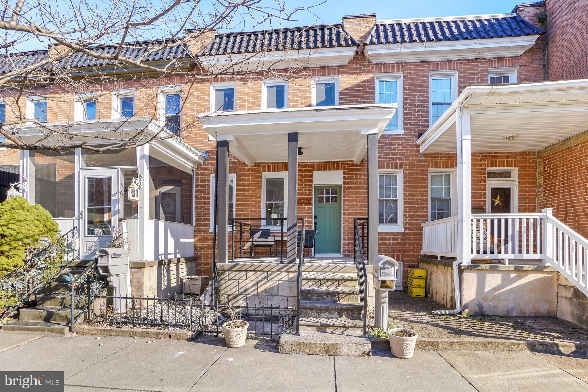 Top-to-bottom renovated 1875 brick rowhome in the heart of Locust Point, two blocks from Latrobe Park and the waterfront promenade — with a private fenced parking pad for 2 cars plus ample street parking. The new white shaker kitchen anchors the main level with upgraded quartz countertops, a green glazed-tile backsplash, stainless steel appliances including a Samsung 5-burner gas range, and a seating peninsula open to the living and dining rooms. Wide-plank light oak flooring, recessed lighting, and a black metal horizontal-rail staircase run throughout. Upstairs holds three bedrooms, each with a ceiling fan, and a full bath finished in green glazed tile with matte-black fixtures. A main-level powder room adds convenience. The finished lower level nearly doubles the living space: a family and rec room with double closets, a second full bath with checkerboard tile, and a Samsung front-load washer and dryer. Central air and forced-air gas heat throughout. Outside, a covered front porch faces the block, and a covered rear deck steps down to the fenced 2-car parking pad with alley access. Walk to Fort McHenry, Hull Street Blues Cafe on the corner, and McHenry Row shopping with Harris Teeter, gyms, and restaurants. Quick I-95 access, close to Under Armour HQ and Baltimore Peninsula. Sold furnished negotiable. Move-in ready — schedule your showing today.