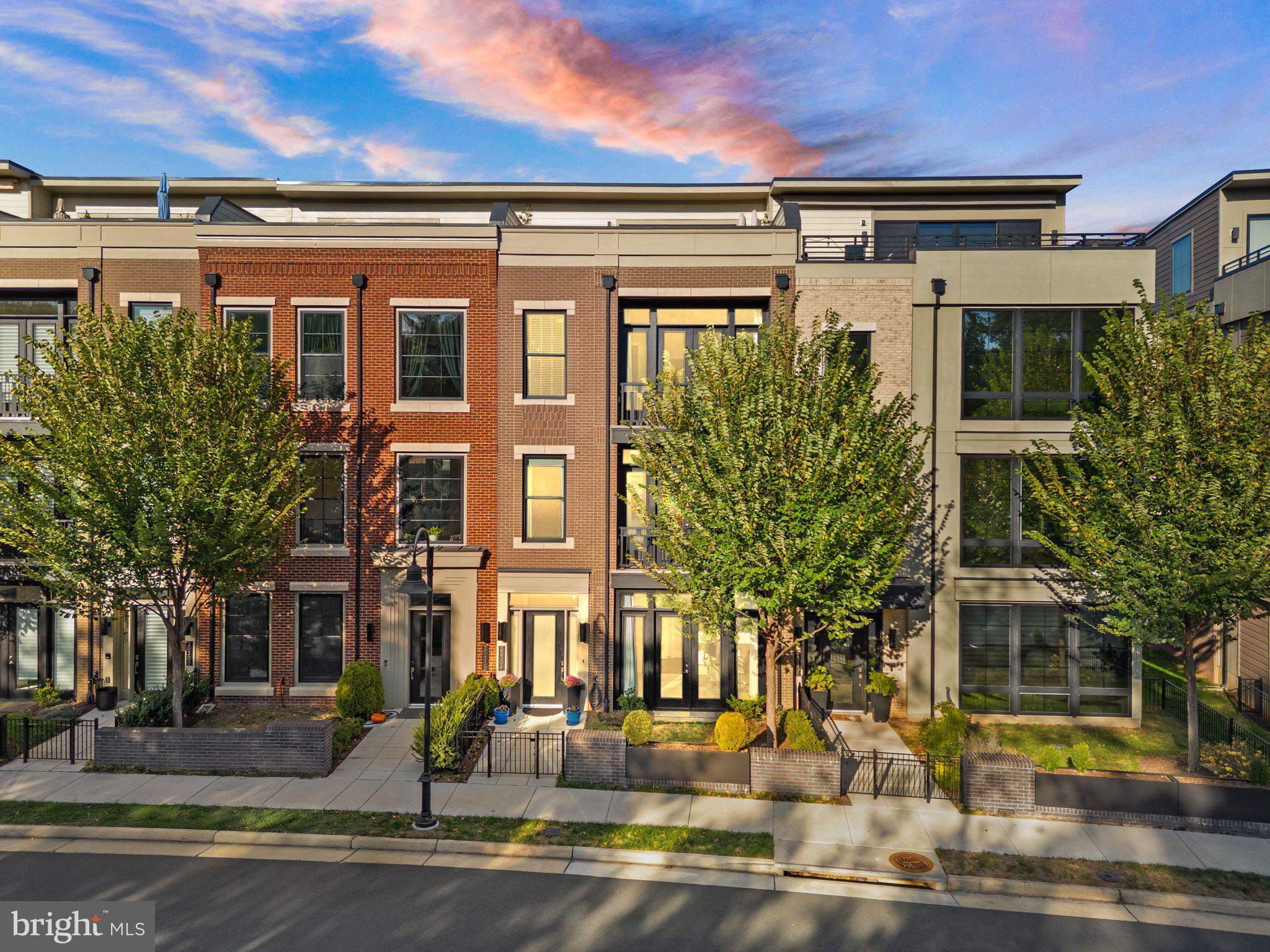 Note: This property is not furnished and the photos are used, with permission, from the previous furnished listing.  Welcome to One Loudoun, where dining, shopping, and entertainment meet sophisticated urban living. Built by Miller & Smith, these award-winning elevator townhomes on Northpark Drive, overlooking One Loudoun's Central Park, are among the most sought-after in the neighborhood, offering tranquil wooded views, direct access to the walking trail, and a true lock-and-leave lifestyle. The home has over $108,000 in post construction upgrades in the last few years. Designer lighting, custom window treatments, rich paint tones, 10-foot ceilings, oversized windows and doors, a true gourmet chef's kitchen, and quartz countertops in the kitchen and all bathrooms elevate every space. A private elevator offers convenience, especially after a day of shopping. Enter through the private gated courtyard to a welcoming foyer framed by tall ceilings, 7-inch baseboards, and sophisticated design elements. The entry level offers a flexible bedroom or office with custom built-ins, a full bath for guests, a cozy patio with oversized doors, a large storage closet, and an expansive two-car garage with ample storage. The main level is the heart of the home, centered around a breathtaking chef’s kitchen featuring a Wolf 6-burner gas cooktop, Sub-Zero refrigerator and wine fridge, Wolf double oven and microwave, quartz countertops, ceiling-height, double tier cabinetry, and an oversized island perfect for gatherings. A walk-in pantry with custom shelving and a stylish dry bar featuring the Sub-Zero wine refrigerator in the dining room enhances the space for effortless entertaining. The dining area is generous in scale, ideal for hosting family dinners or festive celebrations. The deck off the kitchen and dining room offers another relaxing and charming space for this home. In the adjoining family room, a linear gas fireplace with a feature wall and flanked by custom shelving creates a warm, modern space. Soaring ceilings and walls of windows overlook the wooded park, filling the home with light and serenity. Upstairs, the primary suite is a true retreat, featuring high ceilings, an elegant spa-inspired bathroom with a soaking tub and walk-in glass shower, and a private balcony perfect for morning coffee or evening relaxation. The large walk-in closet is fitted with custom built-ins that blend beauty and organization. Two additional spacious bedrooms share a beautifully upgraded full bath, and the laundry room offers abundant cabinetry and storage. The top floor is an entertainer’s dream, designed for casual gatherings or quiet evenings under the stars. This versatile space includes custom shelving, dramatic ceilings, and a wall of sliding glass doors that open to the private rooftop terrace—complete with panoramic views, ideal for dining, lounging, or enjoying sunsets. This exquisite residence seamlessly combines style, sophistication, and comfort with exceptional architectural design and a premier location. It is roughly half a mile to Trader Joe’, Barnes & Noble, Starbucks, and One Loudoun’s shops and restaurants, with easy access to nearby Whole Foods, Costco, Dulles Airport, downtown Leesburg, and Reston Town Center. Luxury, lifestyle, and location unite in this extraordinary One Loudoun home. Amenities are: huge outdoor pool & deck, 3 level clubhouse with indoor basketball, great room, dining hall, and catering kitchen available for rent, yoga studio, sports fields, sand volleyball court, tennis & pickleball, small fenced dog park, a newly constructed playground, and scheduled community entertainment at the outdoor Barn.
