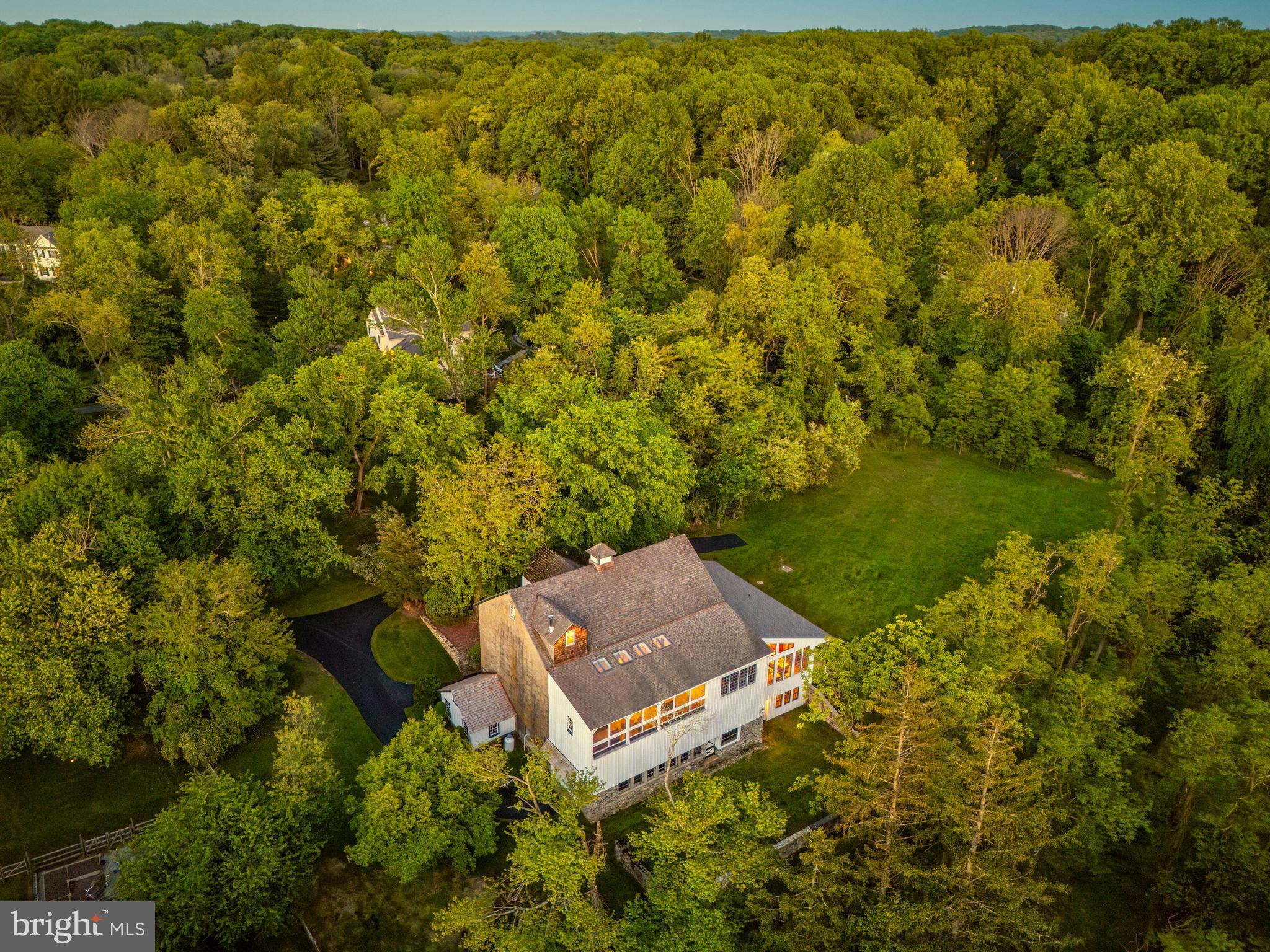 Have you always wanted to live in an historic property? How about a converted barn "Dream Home"?  This exceptional property will be the "Dream Home" featured in the October issue of County Lines magazine! This converted, restored bank-barn (circa 1831) is nestled on 2.5-acres in Malvern, Willistown Township., offering the perfect balance of privacy with the convenience of a Main Line location. Enjoy sunset views over a lovely meadow with a meandering stream, and regular sightings of local wildlife including a red-tailed hawk, fox, and (a very handsome!) heron. This exceptional property has been artfully restored and renovated, balancing respect for the past with updates for today's busy lifestyles - including a spacious main level home office, with the option for a second office. All four bedrooms have ensuite bathrooms, offering privacy for you, family members and guests.  Throughout this property you'll find exposed stone and re-claimed barn wood walls, wide-plank hardwood flooring, mortise and pegged posts and beams, and custom cabinetry (from local craftsman).  Even ceilings were rebuilt, removing old sheetrock, adding new insulation, recessed lighting, and reclaimed hemlock and ash planking.  Other highlights include the large three-season screened porch overlooking the peaceful stream and woods beyond.  Nicely removed from the main house for quiet and privacy, the spacious office is accessed from the screened porch by its own separate door. With a vaulted ceiling, floor-to-ceiling cabinetry and bookshelves made from reclaimed barn-wood, this space is truly "magazine worthy".   Also on the main level is a cozy den (possible second office), a powder room, main floor laundry, plus living and dining rooms with soaring exposed stone walls. The kitchen features custom-crafted cabinetry with under-mount lighting, a large center island with prep sink and second oven, plenty of storage, recessed seating, and pendant lighting. In keeping with the restoration of the home, the turned hardwood stairs to the upper level are from an old school building in Kennett Square. All four bedrooms in this home have exposed hardwood flooring, private baths, and walk-in closets. There are two bedroom suites on the upper level (including the primary suite and one guest room), plus two more bedroom suites on the lower (daylight walk-out) level. The primary bedroom suite is “king-sized” with a vaulted ceiling, two large closets (one cedar and one with floor-to-ceiling custom-built cabinetry), plus an updated primary bath with both a shower and period-appropriate soaking tub.  Adjacent to the primary suite, there is an upper-level loft: a great reading nook, and the perfect place to sit, relax and admire the views of the meadow and stream. (With western exposure from the porch, sunset viewing will be a favorite pastime!) From the kitchen, you'll pass through thick, old stone walls into the "corn crib" - now a charming breakfast room, overlooking the lower-level family room. The sunny family room has a vaulted two-story ceiling and a wall-of windows with private, wooded views. A convenient sliding door from the family room offers separate, private access to this level. On the lowest level of the “corn crib”, you’ll find a large bonus room that is currently used as art studio. With an outside entry and roughed-in plumbing for a bath, this space could be another independent bedroom suite, a gym, or yoga room – whatever suits your lifestyle.  With plenty of finished and unfinished spaces available, there is ample opportunity create your own special vision for this very special property.  Historic charm without historic preservation restrictions. Located just minutes from major commuting routes, the charming borough of Malvern, Main Line shops, restaurants, and host of golf and country clubs. This special oasis offers an escape from hectic-paced lives, within easy commuting distance to Philadelphia, NYC and Washington, DC.