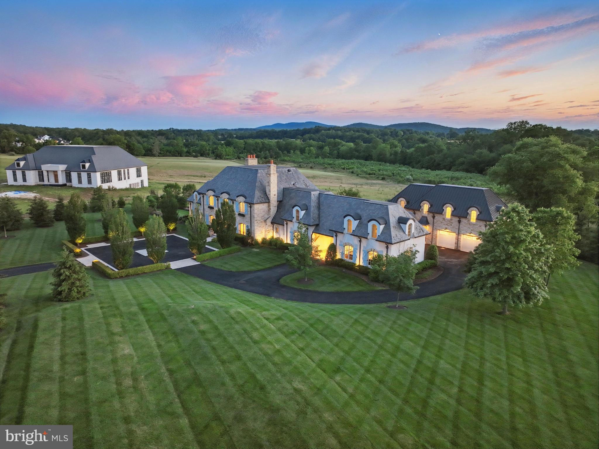 Set within the prestigious gates of Creighton Farms, 22805 Creighton Farms Drive is a meticulously crafted estate that blends timeless elegance with elevated modern living. Thoughtfully designed across three finished levels and complemented by a private carriage house, this residence offers both grand scale and refined comfort at every turn.

The main level is anchored by beautifully appointed living spaces, including a formal dining room with a gas fireplace, custom built-ins, and designer lighting. A fully equipped wet bar with Sub-Zero refrigeration enhances the home’s entertaining capabilities, while the chef’s kitchen serves as a true centerpiece—featuring stone countertops, a statement LaCanche range with pot filler, Vent-A-Hood designer hood, Sub-Zero refrigeration with integrated drawers, a Wolf coffee system, and exposed wood beams. The kitchen flows seamlessly into a sunlit breakfast nook and an inviting family room with fireplace, built-ins, and French doors. A private office wrapped in windows, a functional mudroom with stone flooring and built-ins, and a walk-in pantry add both style and practicality.

Upstairs, five spacious en-suite bedrooms provide comfort and privacy, along with a secondary wet/coffee bar. The primary suite offers a serene retreat with tray ceilings, a gas fireplace, automated window treatments, and French doors opening to a Juliet balcony. The spa-like bath features dual vanities, a Victoria + Albert soaking tub, steam shower, water closet, and a custom walk-in closet with built-in vanity. A dedicated laundry room with LG appliances completes the level.

The lower level is designed for lifestyle and leisure, featuring a wine cellar, expansive entertainment room, private theater, exercise studio, and an additional bedroom with full bath. Outdoor and indoor spaces are seamlessly connected through a covered living area with brick flooring, a wood-burning fireplace, and retractable screens—perfect for year-round enjoyment.

A detached carriage house adds exceptional flexibility, offering its own living quarters with a mudroom entry, flexible main-level living space, and two bedrooms with a full bath above. Complete with a five-car garage, dual staircases, Perrin & Rowe fixtures, and professional landscaping, this residence delivers a rare opportunity to experience luxury living at its finest.