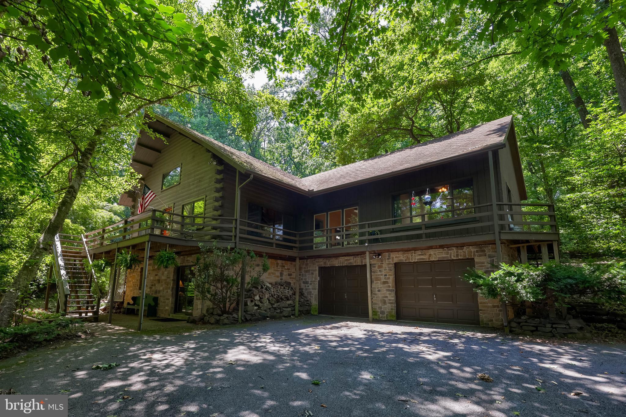 Welcome to 5680 Bull Road—a one-of-a-kind log home offering 3 bedrooms, 2 full and 1 half baths, and over 3,300 square feet of finished living space on 3.16 private, wooded acres in Dover Township. Blending rustic character with modern comfort, this remarkable property offers a peaceful retreat surrounded by mature trees, beautifully landscaped grounds, and exceptional outdoor living spaces designed to embrace its tranquil setting.

Inside, the home welcomes you with soaring ceilings, exposed beams, handcrafted wood details, and an abundance of natural light that highlight the warmth and craftsmanship found throughout. The impressive great room serves as the heart of the home, featuring a soaring cathedral ceiling, skylights, custom built-ins, and a magnificent wood-burning fireplace crafted from stone harvested directly from the property, creating a truly one-of-a-kind focal point that reflects the home's connection to its natural surroundings. Flowing seamlessly from the great room, the formal dining area offers vaulted ceilings and built-in accents, creating an ideal setting for entertaining family and friends.

The spacious eat-in kitchen combines rustic charm with everyday functionality, featuring granite countertops, a center island with breakfast bar seating, custom built-ins, and abundant cabinetry. Thoughtfully designed for entertaining, the oversized island extends seamlessly into the formal dining room, creating an effortless connection between the two spaces that encourages conversation, simplifies serving, and allows gatherings to flow naturally throughout the home. Just off the main living areas, a comfortable den with vaulted ceilings and built-ins provides the perfect place to unwind, while a separate office offers flexible space for working from home, hobbies, or a quiet reading room. The main-level primary suite creates a private retreat with a walk-in closet and a beautifully appointed en-suite bath featuring a walk-in shower and timeless finishes. Main-floor laundry hookups add additional convenience for single-level living.

Upstairs, two generously sized bedrooms feature cathedral ceilings, hardwood flooring, built-in storage, and charming architectural details that complement the home's log construction. A spacious Jack-and-Jill bath serves both bedrooms, creating comfortable accommodations for family and guests alike.

The finished walkout lower level significantly expands the home's versatility, offering a spacious recreation room anchored by a second wood-burning fireplace, creating the perfect setting for movie nights, game days, or entertaining. A half bath, utility room, workshop space, and additional built-in storage further enhance the functionality of this level while providing exceptional space for hobbies, projects, and organization.

Outdoor living is equally impressive, with a wraparound deck, partially covered paver patio, gazebo, and a large fenced in-ground pool creating an exceptional private retreat for entertaining or relaxing. The beautifully landscaped grounds, mature trees, and wooded surroundings offer outstanding privacy while allowing you to enjoy the peaceful sights and sounds of nature from every angle. An oversized attached two-car garage with basement access and additional storage completes this remarkable property.

Offering the charm and craftsmanship of a classic log home with spacious living areas, exceptional outdoor amenities, and a picturesque wooded setting, 5680 Bull Road presents a rare opportunity to enjoy country living while remaining convenient to York, shopping, dining, and major commuter routes. Schedule your private showing today!