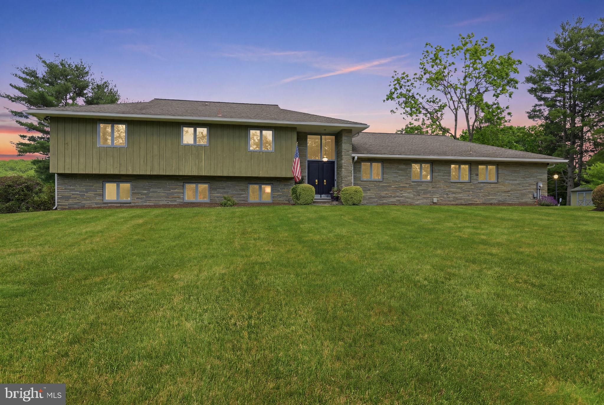 A rare gem in Upper Makefield's Village of Woodhill, this exceptional mid-century modern residence sits on more than two private acres overlooking Jericho Mountain. Delivering a striking blend of architectural character and comprehensive luxury within the highly acclaimed Council Rock School District, this 4-bedroom, 3 ½ bathroom property offers artistic design and sophisticated elegance. Having undergone an extensive top-to-bottom renovation, the residence has been thoughtfully reimagined - updating every room, surface, and fixture while honoring the iconic clean lines and impressive scale of the original 1971 design.

Approaching the home, you are immediately greeted by a period-authentic facade featuring an organic mix of natural stone and vertical board-and-batten siding, anchored by a dramatic, two-story recessed entryway. Inside, the renovation masterfully maximizes natural light and accentuates the property's stunning, picturesque views at every turn.

The entry level opens up for fluid movement, with brand-new Brazilian white oak engineered hardwoods running seamlessly through bright spaces accented by high-end designer lighting. The foyer leads directly into a showstopping chef’s kitchen designed for high-end entertaining, where a massive central island offers seating for five and opens to the main living room. The kitchen is beautifully complemented by honed granite countertops, a marble backsplash, and appliance garages for clutter-free surfaces. Premium amenities include a 6-burner dual-fuel KitchenAid range with private propane service, dual dishwashers, two refrigerator drawers, a kitchen wet bar, and a walk-in pantry. This level flows into a formal dining room and the expansive main living room, where a soaring floor-to-ceiling fireplace in rough-cut marble sits alongside large windows framing the home's finest views. A renovated powder room and a finished laundry room complete this floor. All interior doors across the upper two levels have been widened and replaced with solid hardwood, amplifying the sense of volume.

The upper level hosts the sleeping quarters, beginning with a restful primary suite featuring elegant bedside hanging pendants, pocket doors to dual custom closets, and a luxurious bath with a modern, seamless no-lip rainfall shower entry. Two additional spacious bedrooms share a beautifully renovated hall bath.

The garden level reveals an equally impressive retreat, where rich paneling and warm colors balance the home's bright aesthetic. This level is anchored by an oversized family room with a stone floor-to-ceiling fireplace and the original 1970s wet bar, tastefully preserved as a nostalgic homage to the period. A private guest suite provides a dedicated sanctuary, served by a full bathroom where the original vintage tile is perfectly paired with complementary floral wallpaper. Completing this floor are a home office with custom built-in shelving, and an expansive, flexible bonus room with classic parquet floors, soaring ceilings, and a direct step-out to the outdoors - perfect for a studio, gym, or playroom.

Outside, a tiered Pennsylvania bluestone patio connects both levels for outdoor living. Looking directly toward Jericho Mountain in serene privacy, this area showcases incredible long-distance views and sunsets. The grounds feature a private tennis court - ideal for a pickleball conversion - and a two-car garage outfitted with custom hardwood cabinetry and a new custom garage door with opener.

Notable updates include a new HVAC unit with heat pump (2024), a new water heater (2023), and new chimney liners (2021). Completely move-in-ready, this home offers the perfect blend of country privacy and suburban convenience, situated just minutes from the boutiques and dining of Newtown, New Hope,  and Yardley Boroughs, with easy commuting access to Princeton, Philadelphia, and New York City.