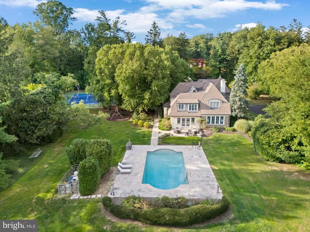 This elegant stone Tudor sits on almost three acres on one of the most coveted streets in Rydal. As you step into the turreted entrance onto the marble foyer floor, to your left is a spacious living room with a wood burning fireplace along with an adjacent sitting area overlooking the gardens.  To your right is the dining room that flows through the butlers pantry and into the updated gourmet kitchen with a sub zero, granite counters, double built in ovens, and an abundance of high end cabinets with slow close drawers. Off the kitchen there is a half bath and around the corner is an expansive family room that adjoins a large playroom overlooking the pool. Upstairs there is the large primary bedroom with en suite bathroom, along with an attached dressing room with multiple closets. A second bedroom has a sitting room and also has en suite bath and the two additional bedrooms share a hall bath.  Through the breezeway off of the kitchen, you will find a newly built three car garage that offers guest quarters above with a bedroom, full bath and a separate HVAC system. The grounds are magnificent! There is a beautiful salt water pool surrounded by Travertine paving There is a full size tennis and pickleball court, a slate patio that's perfect for outdoor dining, and many mature trees and hedges that provide privacy to the grounds.  The location can't be beat. The property adjoins the twenty acre Crosswicks Wildlife Refuge and is minutes from Whole Foods, Trader Joes, many casual and fine dining restaurants, shopping, and Septa regional rail for an easy ride to Center City.  Special homes like this don't come on the market very often.  Schedule your showing today.