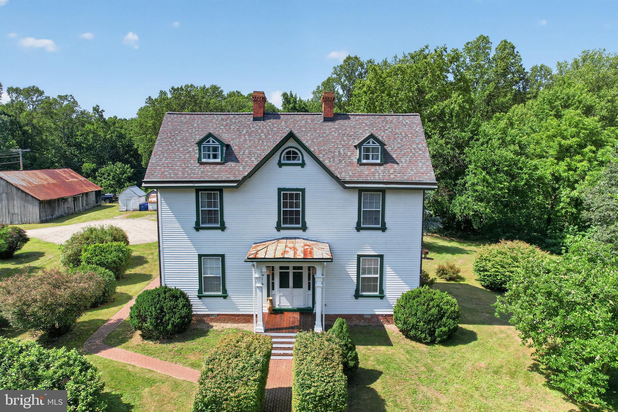 Step back in time without sacrificing modern convenience at this truly one-of-a-kind historic estate. Originally built in 1846 with a separate kitchen dating back to 1836, this remarkable property seamlessly blends nearly two centuries of history with extensive modern updates. Situated on two lots totaling nearly 10 acres, including approximately 9 acres of usable wooded land with established ATV and dirt bike trails and excellent potential for recreation or hunting, opportunities like this are exceptionally rare.

The grounds are nothing short of spectacular, featuring an authentic historic tobacco barn along with several original outbuildings including a smokehouse, chicken coop, and even the original outhouse, preserving a fascinating piece of Maryland's agricultural history. A modern detached two-car garage offers generous space for vehicles and equipment, while the full second-level loft provides abundant storage.

The current owners have invested extensively in the home's infrastructure, allowing the next owner to enjoy historic charm with modern peace of mind. Major improvements include a complete electrical replacement with new wiring, outlets, switches, and an upgraded service panel (2022), eight wall-mounted mini-split heating and cooling systems (2021), a brand-new architectural shingle roof (2025), and a freshly painted exterior (2026).

As you enter this magnificent three-level home offering approximately 3,334 square feet of finished living space, you'll immediately appreciate the grand center hall, soaring 11-foot ceilings on the main level, six original fireplaces, oversized rooms, and breathtaking craftsmanship throughout. The original random-width hardwood flooring, stunning crown molding, oversized trim, and beautifully preserved woodwork showcase a level of quality that simply cannot be replicated today.

The heart of the home is the beautifully updated kitchen, where historic character meets modern luxury. Features include premium cabinetry, granite countertops, a center island, built-in bench seating, stainless steel appliances, a commercial-grade gas range with professional hood, a newer refrigerator (2024), and an incredible 10-foot vaulted ceiling with exposed rafters that creates a warm and inviting gathering space.

Just outside the kitchen, the charming covered rear porch serves as a true extension of the home, overlooking the expansive backyard, patio, and a former fish pond ready to be restored. Whether enjoying your morning coffee or entertaining guests, this peaceful outdoor space is sure to become a favorite.

Inside, the formal dining room is simply stunning, featuring one of the home's six fireplaces, now accented with a pellet stove for added warmth and efficiency. Two enormous family rooms, each showcasing oversized historic fireplaces with massive fireboxes, provide unforgettable spaces for entertaining and everyday living.

The second level continues to impress with nearly 10-foot ceilings, three oversized bedrooms, three additional fireplaces, a beautifully updated full bath, convenient laundry area, and the same incredible random-width hardwood floors and original trim found throughout the home.

The finished third floor offers exceptional flexibility and is currently used as an expansive primary suite complete with a half bath and two dedicated mini-split systems for year-round comfort. This remarkable space spans nearly the entire upper level and could easily serve as a luxurious owner's retreat, guest suite, studio, office, or recreation room.

From its rich history and irreplaceable architectural details to its thoughtful modern improvements and nearly 10 acres of beautiful land, this extraordinary property offers a once-in-a-lifetime opportunity to own a true piece of history. Homes of this caliber, character, and setting rarely become available. Schedule your private tour and experience everything this remarkable estate has to offer.