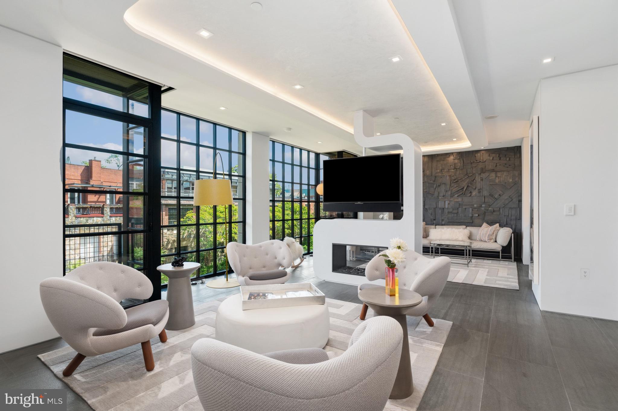 Perched on the 6th floor of the prestigious 3303 Water Street Condominium  - this extraordinary residence is a masterclass in quiet luxury, bringing together bespoke design and one of Georgetown’s most sought-after waterfront settings. Residents experience privacy, white-glove service, and first-class amenities at 3303. This fully reimagined two-bedroom, two-bath home was conceived not simply as a residence, but as an immersive living experience.

Behind the doors of this full-service condominium, an exquisitely curated interior unfolds, created in collaboration with acclaimed FORMA Design. Every inch of the residence was transformed to create a home that feels open, expansive, and undeniably refined.

The result garnered national acclaim, featured as the cover story of the January/February 2019 issue of HOME & DESIGN Magazine, highlighted in FORMA Design’s “Ultra-Modern Flat in the Nation’s Capital,” and showcased as the cover story of The Washington Post Real Estate Section.

Inside, heated Concordia Velvet large-format stone flooring flows throughout the residence, powered by Schluter radiant heat systems for year-round comfort. A dramatic custom double-sided Sparks fireplace centers the living and lounge spaces, paired with dual integrated flat-screen TVs and enveloped by sophisticated architectural millwork. Venetian plaster cove ceilings add depth and dimension throughout the main living areas. Sleek Poliform cabinetry with touch-activated openings elevates the kitchen into a sculptural centerpiece complete with Silverstone countertops, a custom dining table, and premium Sub-Zero and Miele appliances.

Technology and ambiance exist in perfect harmony. A fully integrated Crestron automation system controls lighting, audio, and entertainment with precision. Designer Lightolier recessed LEDs, a FLOS dining chandelier, and integrated lighting details create an atmosphere that shifts beautifully from day to evening.

Designed with remarkable versatility, the secondary bedroom functions beautifully as a sophisticated office or lounge space while easily converting into a private guest suite with its integrated Murphy bed by Clei—Italy's premier manufacturer known globally for pioneering high-end transforming furniture. Thoughtfully designed for effortless use, the bed can be deployed without disrupting the office shelving and built-ins, making the transition both practical and convenient. Full-height custom wood-and-glass pocket doors provide privacy when guests arrive, while a breathtaking fiber-optic “starry sky” ceiling transforms the room into an unforgettable retreat.

In the primary suite, smokey mirrors and a custom leather headboard amplify the sense of scale and serenity, while the spa-inspired bath introduces a luxurious double shower, integrated flat-screen TV within the dual-vanity mirror, and fully automated Kohler bidet toilet with heated seating and remote operation.

Every finish, fixture, and architectural detail was selected without compromise, from Maharam wallcoverings and Dreamwalls color glass accents to custom hardware and integrated AV solutions. This is not simply a condominium; it is a collectible design residence hidden above one of Washington’s most historic and picturesque corridors.

A rare opportunity to own a Georgetown showpiece where architecture, technology, and craftsmanship converge at an extraordinary level.