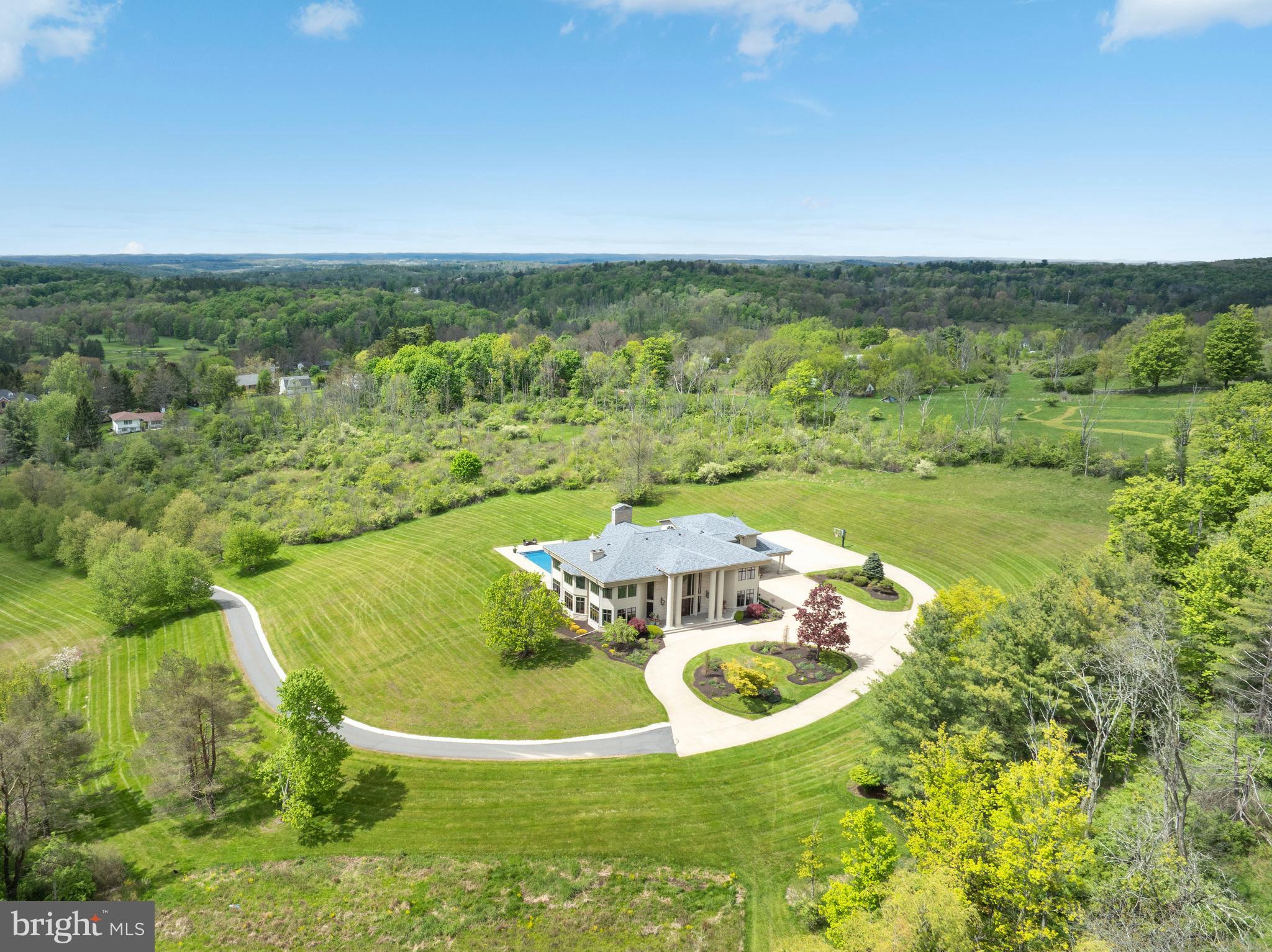 Experience luxury at its finest in this extraordinary contemporary estate nestled in Waverly Township. Offering 24.8 acres and over 10,000 sqft of living space with five bedrooms, five full baths, and two half baths, this residence seamlessly blends sophistication, comfort, and exceptional amenities. The property provides convenient access to Abington Heights School District, shops, dining, country clubs, outdoor recreation in Clarks Summit, and Lackawanna State Park. Approximately 7 miles from Scranton preparatory, 20 miles from Wyoming Seminary, 65 miles from Blair Academy in Blairstown NJ, also nearby University of Scranton, Commonwealth Medical School, Penn State University, 11 miles from Montage Mountain featuring concerts, skiing, water park, and shopping, 16 miles from Elk Mountain Ski Resort, 30 minutes from the Pocono Mountains, and only two hours from both NYC and Philadelphia.

A tree-lined entrance welcomes you to the circular driveway, breathtaking mountain views create a stunning first impression. Designed for relaxation and entertaining, the outdoor living spaces are exceptional, an inground saltwater pool with HydraPure filtration system and electric safety pool cover, expansive patios, a pool/sitting room with bath, inviting back porch, fire pit, and landscaped grounds that create a private retreat ideal for hosting guests. Additional highlights include three gas fireplaces, a elevator with access to the main and second levels, and two separate staircases to the upper floor.

Inside, the dramatic two-story marble foyer features recessed lighting, chandelier, and a magnificent bifurcated staircase. Flowing seamlessly from the foyer, the formal dining room showcases hardwood floors, crown molding, wainscoting, and elegant lighting, the adjacent butler’s pantry offers built-in cabinetry, recessed lighting, hardwood flooring, and access to a second walk in pantry.

The chef’s kitchen is thoughtfully appointed with hardwood floors, two oversized islands, commercial-grade hood vent, wet bar with overhead lighting, double ovens, two warming drawers, separate Sub-Zero refrigerator and Sub-Zero freezer, and a premium six-burner range with optional wok station, cast iron grill, and griddle. Just beyond, the breakfast area overlooks the patio and pool, while the adjoining great room impresses with hardwood floors, coffered ceiling, crown molding, and a striking 29 feet limestone gas fireplace, along with direct patio access for seamless indoor-outdoor living.

The main level also features a spacious media room with built-in cabinetry, speakers, carpeting, and French doors leading outside; an elegant front living room with hardwood flooring and gas fireplace; a private office/study featuring custom mahogany paneling and floor-to-ceiling built-in shelving; two half baths; spacious laundry room; and a full bath with a steam shower.

Upstairs, the luxurious primary suite serves as a private sanctuary featuring recessed lighting, gas fireplace, sitting area, and two expansive walk-in closets with custom built-ins. One closet includes additional flex space ideal for a hobby room or fitness area. The spa-inspired primary bath offers an oversize jetted tub, steam shower, and water closet. Four additional generously sized bedrooms, convenient walk in cedar closet, two full baths, and an additional laundry room finish the upper level.

The expansive lower level offers approximately 5,000 square feet of additional space with vinyl flooring and endless possibilities for recreation and entertainment, along with an additional full bath.

Completing the property is a heated 4-car garage with Tesla car charger and parking accommodations for up to 10 vehicles in the expansive driveway. This exceptional Waverly Township estate masterfully combines timeless elegance, luxurious amenities, and extraordinary living spaces into one unforgettable property. Schedule your private tour today.
