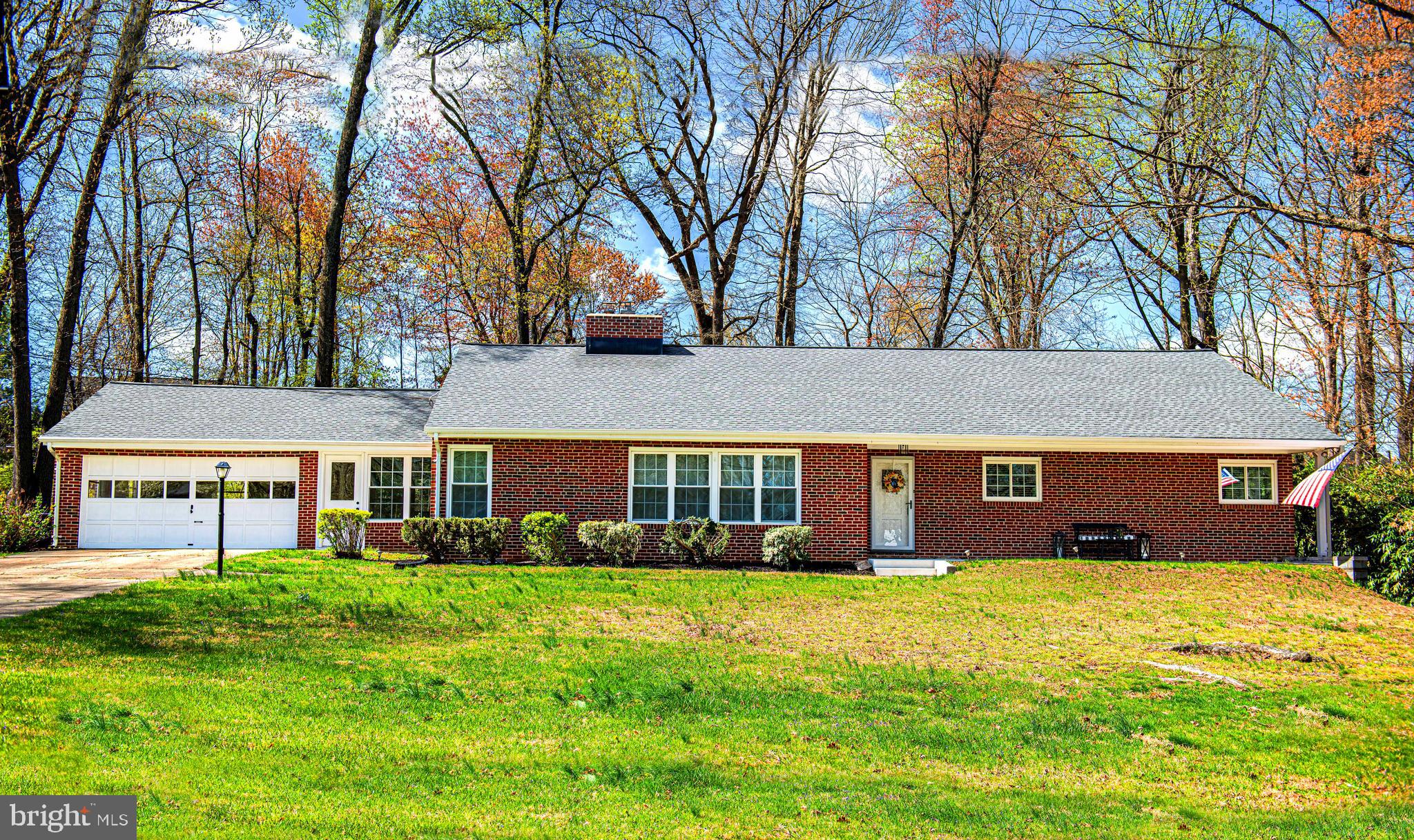 Don't miss this sprawling brick rancher on a lovely 1.43 acre lot backing to trees! The covered front porch (rebuilt 2022) welcomes you in, showcasing original hardwood floors throughout most of the almost 2200 sqft of living space on the main level. Enjoy entertaining in the huge living room with bright windows and a wood burning stove insert (2016 - new chimney liner and exterior chimney rebuilt then, too); and the kitchen and formal dining room that feature views of the beautiful treed lot and brick patio. Convenient "breezeway" off kitchen makes easy access to the 2-car garage, driveway, and backyard. The great layout continues with three large bedrooms, all with hardwood floors and ceiling fans. Find the completely updated hall bathroom, and the ensuite primary bathroom with original vintage tiles. The huge, clean, unfinished basement is ready for your fun - with plenty of natural light and large windows. Bring your finishing touches as the "big" projects have already been completed - new basement windows (2025), updated plumbing and electrical breaker panel (2023), architectural shingle roof (2021),  main level windows (2021),  incoming electric feed line (2021), chimney rebuilt & liner installer (2016), central air system (2016), boiler and water heater (2016).