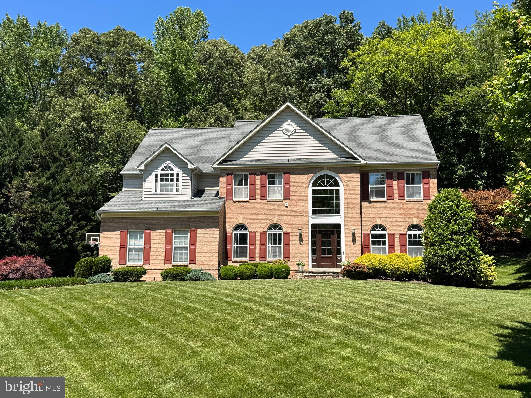 Tucked away on a quiet no-through street in one of Davidsonville's most desirable settings, this impeccably maintained brick-front Colonial on nearly an acre offers the perfect blend of timeless architecture, thoughtful updates, and exceptional indoor-outdoor living.
A dramatic two-story foyer welcomes you inside, highlighted by a new large arched architectural window that fills the home with natural light, soaring cathedral ceilings, and refinished hardwood flooring. The main level features elegant formal living and dining rooms enhanced with crown molding, chair rail detailing, oversized windows, and abundant natural light. The updated kitchen is designed for both everyday living and entertaining, offering granite countertops, a large center island, custom porcelain tile flooring, stainless steel appliances, a built-in desk area, and a picturesque 10 ft bay window overlooking the backyard. Sliding glass doors from the breakfast area lead directly to the expansive IPE Brazilian hardwood deck, seamlessly connecting indoor and outdoor living spaces.
Just off the kitchen, the impressive sunken family room showcases an 11-foot ceiling, gas fireplace with custom mantel, oversized windows with transoms, and beautiful views of the landscaped grounds. A private first-floor office or optional guest bedroom with an adjacent full bath provides flexibility for today's lifestyle needs.
The upper level features a generous freshly painted primary suite with vaulted ceilings, a spacious sitting room, dual walk-in closets, and a spa-inspired bath with double vanity, soaking tub, and separate shower. Three additional bedrooms, an updated full bath, a convenient upper-level laundry room, and pull-down access to a floored attic complete the second floor.
The finished walk-out lower level offers exceptional versatility with a spacious recreation and entertainment area featuring porcelain tile flooring, recessed lighting, a custom bar area, custom hardwood doors, and direct access to the backyard. A half bath and substantial additional space provide endless possibilities for a workshop, fitness area, hobby room, storage, or future customization.
Outdoor living is equally impressive with a premium two-level Brazilian IPE hardwood deck, extensive landscaping and professional outdoor LED lighting, a full irrigation system, and a dedicated play/sports area—creating the perfect backyard for everyday living and entertaining. The private .94-acre lot backs to a wooded open area and enjoys open space across the street, creating a serene setting rarely found. At the end of a charming tree-lined path, a spacious 12' x 16' shed with electric provides additional storage and functionality.
What truly sets this property apart is the level of care and investment throughout. Recent improvements include dual HVAC systems replaced in 2022 and 2025, UV air purification, a new arched architectural window, new exterior doors, freshly painted interior spaces, and freshly painted exterior shutters. Additional features include a reverse osmosis drinking water system, underground irrigation, emergency battery backup sump pumps,  and an upgraded constant pressure well pump.
Combining classic Colonial design with extensive updates, meticulous maintenance, and a picturesque setting, this exceptional property offers the privacy of a peaceful retreat while remaining conveniently located near Annapolis, shopping, dining, and major commuter routes including Routes 50, 97, and 301.