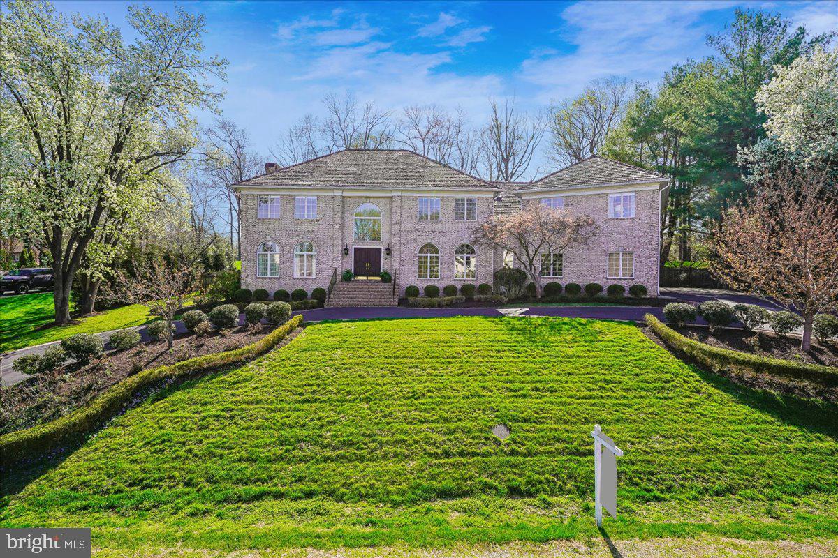 Tucked away on nearly a full acre at the end of a quiet cul-de-sac, this beautifully maintained brick Colonial offers 7,719 square feet (recently remeasured) of comfortable, light-filled living space. Thoughtfully built and cared for by its original owner, the home blends classic design with a warm, welcoming feel throughout.
A circular driveway and side-load three-car garage create an impressive arrival, while inside, a two-story marble foyer and sweeping staircase provide an elegant introduction. The main level offers wonderful spaces for both everyday living and entertaining, including a private library with custom built-ins, a gracious living room with tall windows and fireplace, a formal dining room, and a spacious family room with a stone fireplace and easy access to the patio.
The kitchen is both beautiful and functional, featuring antique white cabinetry, marble countertops, a striking marble backsplash, and high-end appliances including a six-burner Dacor gas range and double ovens. The sunny breakfast area—with vaulted ceiling, skylights, and a cozy window seat—overlooks the peaceful backyard. A sunroom with cathedral ceiling, skylights, and its own fireplace provides the perfect spot to relax year-round.
Upstairs, hardwood floors run throughout five generously sized bedrooms, including a spacious primary suite with a tray ceiling, walk-in closet with custom shelving, and a spa-like bath with soaking tub and dual vanities. The finished lower level offers plenty of flexibility with a large recreation room, wet bar, wine room, game space, den or optional sixth bedroom, and full bath. 
Out back, the private, tree-lined yard feels like a retreat, highlighted by a stunning 1,400+ square foot flagstone patio—ideal for gatherings or quiet evenings outdoors—with plenty of room to add a pool. All of this in a prime McLean location, just minutes to Tysons, Metro, major commuter routes, parks, and sought after Langley pyramid schools.