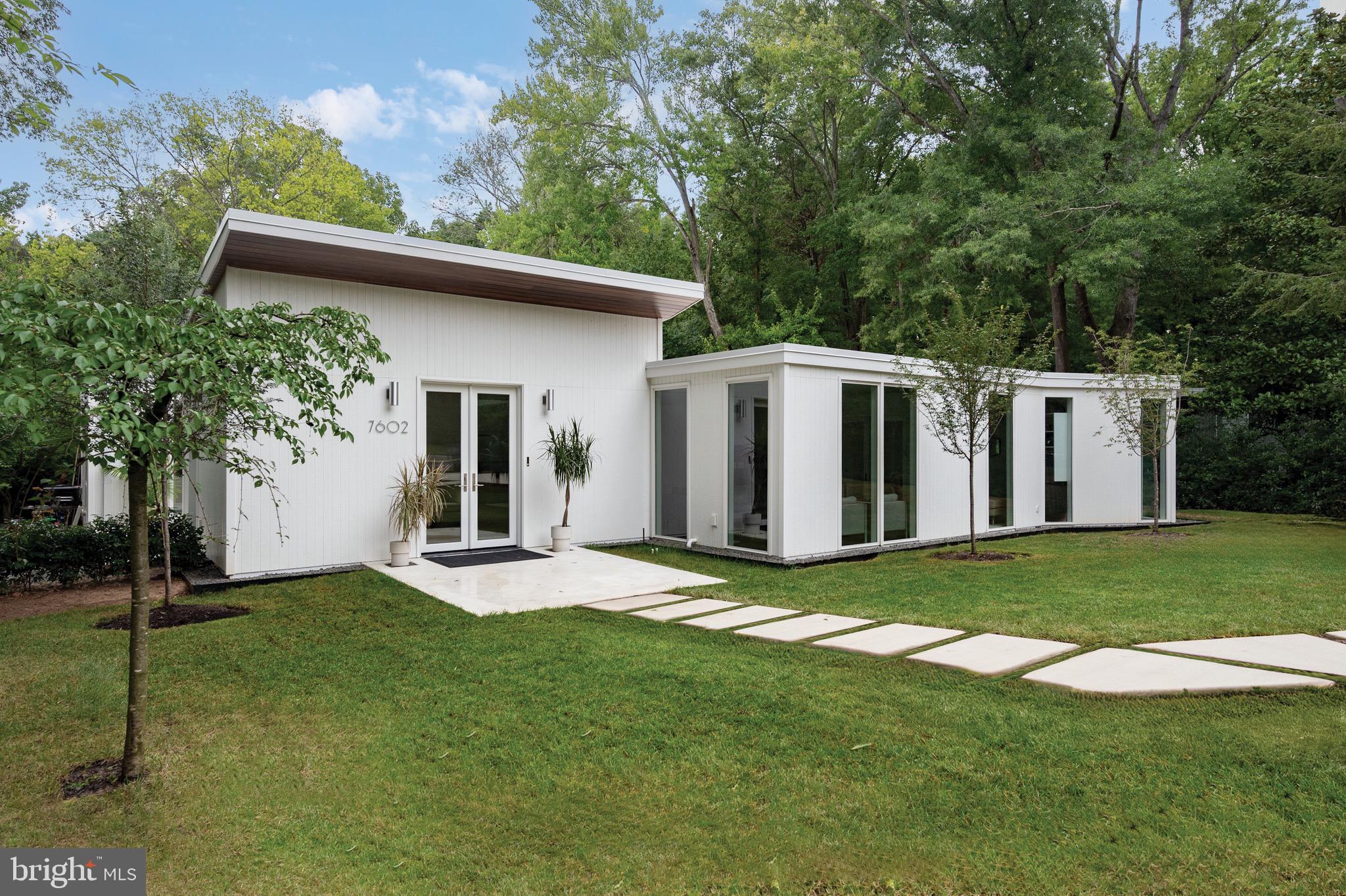 One of the most prestigious homes in Hollin Hills, this one-level mid-century modern residence was designed by renowned architect Charles Goodman. It has been meticulously renovated and expanded with a substantial addition, showcasing extremely high-quality workmanship and luxurious finishes throughout. The home is ideal for entertaining, featuring multiple indoor and outdoor spaces. It includes four bedrooms, three full baths, and one half bath. Upon entering through double glass doors, you are welcomed into a spacious foyer with soaring ceilings, an extra-large built-in coat closet with custom shelving, and a separate family entrance. The open floor plan flows into a living room and a separate dining area with glass doors leading to an inner courtyard. A custom steel and glass pocket door separates the great room and the open kitchen, which boasts custom cabinets, floor-to-ceiling glass tile, an 11-foot island, an eat-in kitchen area, and a great room with 16-20ft ceilings. A stunning wall of glass doors opens to a vaulted covered outdoor area and an expansive patio for entertaining. The very private backyard, backing onto parkland, offers ample space on the flat .39-acre lot, complemented by extensive landscaping and hardscaping, including a new concrete driveway and walkway. The sleeping area is designed for privacy, featuring a luxurious primary suite with spacious custom-built walk-in closets and an en-suite bathroom with a wall of glass shower. Two middle bedrooms share a remodeled hall bathroom, while the back guest bedroom has its own en-suite bathroom. Additionally, there is a separate office with glass pocket doors, perfect for working from home. Every detail in this sun-filled home is custom and intentional, blending mid-century modern design with contemporary luxury.