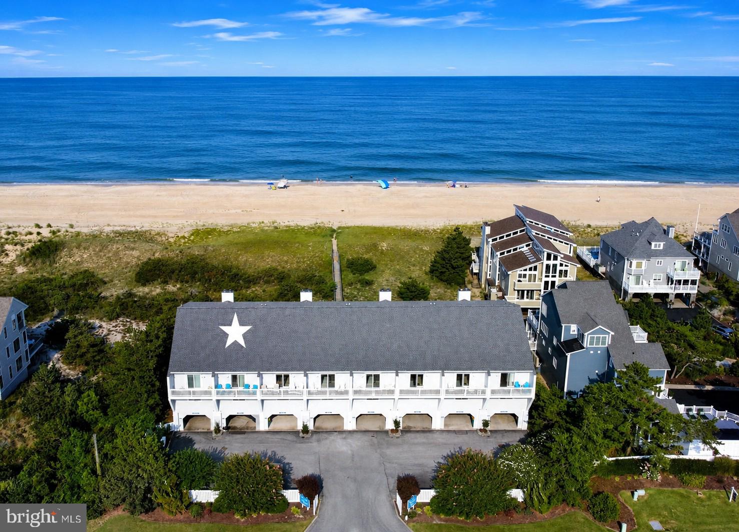 Completely reimagined through an extensive top-to-bottom renovation, this exceptional oceanfront townhome offers the rare opportunity to enjoy luxurious coastal living with sweeping views of both the Atlantic Ocean and Little Assawoman Bay. One of only eight residences in this intimate oceanfront enclave, the home enjoys direct access to the protected beaches of Delaware Seashore State Park. The main living level is designed for effortless entertaining, where an open floor plan is filled with natural light and framed by breathtaking ocean views. The beautifully appointed kitchen features custom cabinetry, quartz countertops, premium stainless steel appliances, and a large island with seating. The kitchen flows seamlessly into the dining and living areas, where expansive sliding glass doors open to a generous oceanfront deck, creating the perfect setting to enjoy the sights and sounds of the Atlantic. A convenient powder room completes this level. The second floor offers two spacious ensuite bedrooms, each with its own private outdoor living space. The oceanfront suite opens to a covered porch overlooking the beach, while the bay-side suite features a private balcony with beautiful sunset views. Each room is complemented by a beautifully renovated bathroom. The top floor is dedicated to the luxurious oceanfront primary suite, featuring breathtaking views from a private beachfront deck and a spa-inspired bathroom. Also on this level is a versatile bonus room with a full ensuite bathroom, providing exceptional flexibility as a home office, media room, fitness space, or overflow accommodations. Every detail of this remarkable residence has been thoughtfully selected, blending timeless coastal design with exceptional craftsmanship and upscale finishes throughout. Additional features include covered parking, an outdoor shower, and an unbeatable Fenwick Island location just moments from restaurants, shopping, and entertainment. Offering the perfect balance of luxury, privacy, and an extraordinary beachfront setting, this is a rare opportunity to own a like-new coastal retreat.