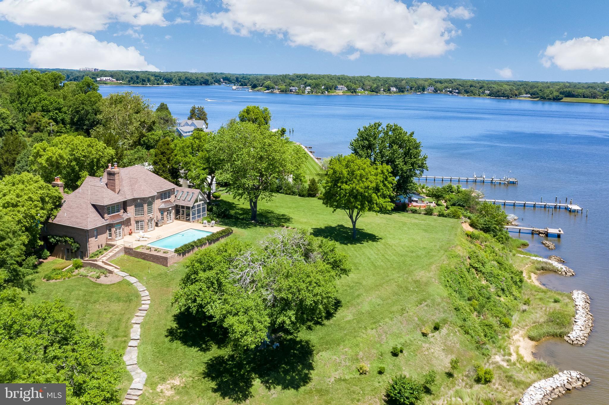 Classically elegant and exquisitely built describes this 5000 sq ft plus, all brick custom home, resting high above Glebe Bay on Larrimore's Point. But what truly sells this property are the breathtaking, full on views of the South River straight out to the Chesapeake Bay!  Add to this a waterside heated pool, the gently rolling slope to 250 ft of water frontage, a 140 ft deep water pier and you have one of the finest waterfronts offered, minutes to Annapolis and centrally located to DC and Baltimore. Key features include, sunny open floor plan with a neutral pallet, designer enhanced high end finishes, expansive living room/ greatroom with floor to  ceiling windows and stone wood burning  fireplace with built-in cabinetry surround, hardwoods and moldings throughout, first floor master suite with fireplace, 2nd floor master en-suite with gas fireplace, 2 additional bedrooms with adjoining baths, stunning gourmet kitchen, gorgeous screened porch, 3 car oversized garage, full walk out basement, 1.7 acres and a beach with $160,000 of seller improved  protected living  shore line. This is a one of a kind offering priced to sell below the recently appraised value.