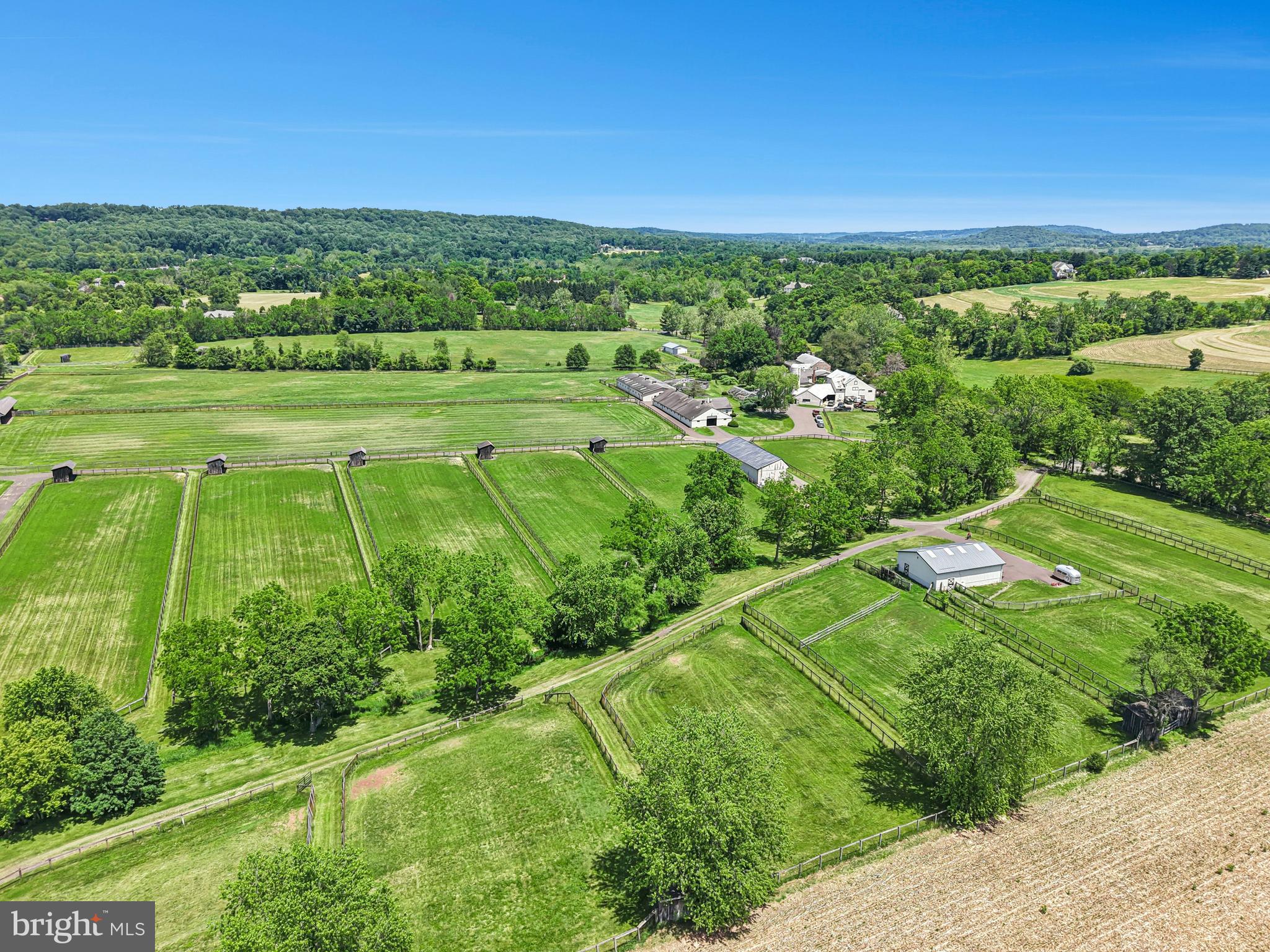 Nestled in the heart of New Hope—one of Bucks County’s most prestigious enclaves—this distinguished legacy estate boasts a storied history as an internationally acclaimed, award-winning standardbred equestrian facility. Encompassing 56 acres of rolling terrain, the property offers a rare synthesis of absolute privacy, sweeping vistas, and architectural significance. As one of the few remaining large parcels in this coveted location free from preservation restrictions, the estate presents an unparalleled opportunity for the discerning investor, equestrian enthusiast, or those seeking a grand country retreat.
     A sweeping driveway traverses the picturesque Pidcock Creek, culminating in a stone-walled courtyard overlooking a landscape of meticulously manicured pastures, while private, paved thoroughfares provide seamless access to the estate’s expansive facilities. 
     The residence, a classic prewar Colonial evocative of an English country manor, stands as a testament to an era of refined craftsmanship. Within, grand proportions define the living spaces, where sun-drenched rooms feature rich, random-width oak flooring and fireplaces of classic design. Every detail speaks to sophistication, from the bespoke cabinetry to the library, a serene sanctuary appointed with oak shelving, a wood-burning hearth, and French doors opening to a 60-foot bluestone patio, an idyllic setting for intimate celebrations or grand garden galas.
     The thoughtful floor plan provides both comfort and luxury, with a gracious first-floor bedroom suite, and 675-square-foot gym featuring a sauna and walk-in shower. French doors open from the gym to a private, covered bluestone patio equipped with a 12-person hot tub. The primary suite serves as a vaulted retreat, complete with a cozy sitting room, stone accent walls, a private deck, and a romantic Mercer-tiled fireplace. A refined dressing room leads to a luxurious travertine ensuite bath, ensuring total indulgence. With seven bedrooms in total, the home effortlessly accommodates family and guests with grace and charm.
     The outbuildings, lovingly maintained by dedicated stewards, offer versatility for a multitude of pursuits. An antique bank barn and a three-car garage provide space for automobile collections, creative studios, or workshops, while three private one-bedroom apartments offer refined accommodations for guests, staff, or estate managers.
     The land itself is an expertly designed canvas, with fenced pastures appointed with waterers and run-in sheds. Equine facilities include an office, equipment building, an automatic walker, and barns boasting 40 stalls—the estate is perfectly equipped to satisfy the most sophisticated of equestrian requirements.
     Fashion Farm stands not merely as a property, but as a stage for cherished memories, a canvas for celebration, and a sanctuary for inspiration.