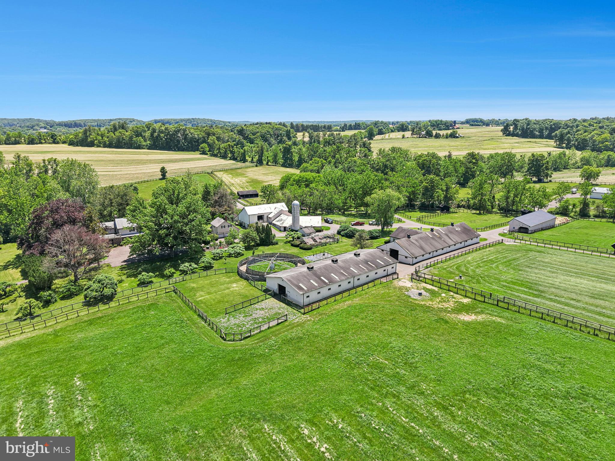 Nestled in the heart of New Hope—one of Bucks County’s most prestigious enclaves—this distinguished legacy estate boasts a storied history as an internationally acclaimed, award-winning standardbred equestrian facility. Encompassing 56 acres of rolling terrain, the property offers a rare synthesis of absolute privacy, sweeping vistas, and architectural significance. As one of the few remaining large parcels in this coveted location free from preservation restrictions, the estate presents an unparalleled opportunity for the discerning investor, equestrian enthusiast, or those seeking a grand country retreat.
     A sweeping driveway traverses the picturesque Pidcock Creek, culminating in a stone-walled courtyard overlooking a landscape of meticulously manicured pastures, while private, paved thoroughfares provide seamless access to the estate’s expansive facilities. 
     The residence, a classic prewar Colonial evocative of an English country manor, stands as a testament to an era of refined craftsmanship. Within, grand proportions define the living spaces, where sun-drenched rooms feature rich, random-width oak flooring and fireplaces of classic design. Every detail speaks to sophistication, from the bespoke cabinetry to the library, a serene sanctuary appointed with oak shelving, a wood-burning hearth, and French doors opening to a 60-foot bluestone patio, an idyllic setting for intimate celebrations or grand garden galas.
     The thoughtful floor plan provides both comfort and luxury, with a gracious first-floor bedroom suite, and 675-square-foot gym featuring a sauna and walk-in shower. French doors open from the gym to a private, covered bluestone patio equipped with a 12-person hot tub. The primary suite serves as a vaulted retreat, complete with a cozy sitting room, stone accent walls, a private deck, and a romantic Mercer-tiled fireplace. A refined dressing room leads to a luxurious travertine ensuite bath, ensuring total indulgence. With seven bedrooms in total, the home effortlessly accommodates family and guests with grace and charm.
     The outbuildings, lovingly maintained by dedicated stewards, offer versatility for a multitude of pursuits. An antique bank barn and a three-car garage provide space for automobile collections, creative studios, or workshops, while three private one-bedroom apartments offer refined accommodations for guests, staff, or estate managers.
     The land itself is an expertly designed canvas, with fenced pastures appointed with waterers and run-in sheds. Equine facilities include an office, equipment building, an automatic walker, and barns boasting 40 stalls—the estate is perfectly equipped to satisfy the most sophisticated of equestrian requirements.
     Fashion Farm stands not merely as a property, but as a stage for cherished memories, a canvas for celebration, and a sanctuary for inspiration.