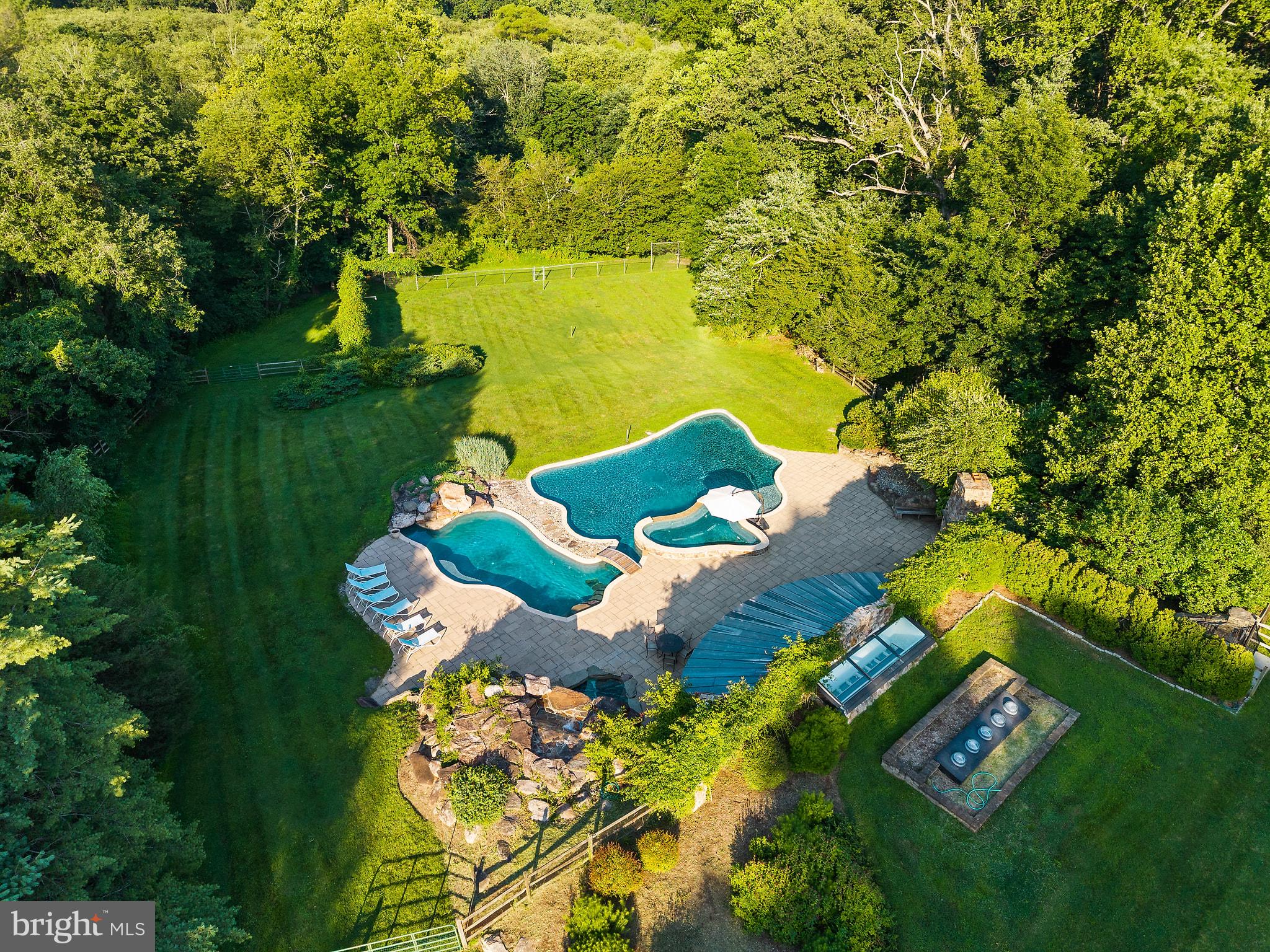 Just minutes from the energy of Tysons and Washington, D.C., discover a private retreat where every day feels like a luxury vacation. Tucked away on an exceptional homesite in one of Vienna's most coveted locations, this remarkable well-built property offers an unparalleled resort lifestyle rarely found in Northern Virginia. The property has also been designated as a Certified Wildlife Habitat by the National Wildlife Federation, reflecting its thoughtfully maintained natural setting.

Designed to rival the finest private resorts, the spectacular outdoor living experience is the true heart of the property. Reimagined in 2011, the backyard is an extraordinary destination for entertaining and relaxation, anchored by a breathtaking lagoon-style pool complete with a cascading waterfall, hidden grotto, diving rock, volleyball area, and expansive spa. Host unforgettable gatherings from the pavilion featuring a fully appointed commercial-grade kitchen, covered dining area, changing rooms for pool guests, and a half bath. Spend evenings gathered around the grand outdoor fireplace. Beyond the pool area, an expansive  lower field extends the resort experience, providing an ideal setting for archery practice, soccer, badminton, family games, or a spirited game of fetch.

Bordering the protected woodlands of Difficult Run Stream Valley Park, the property enjoys the rare privilege of uninterrupted natural vistas and the feeling of owning more than 50 acres of pristine parkland beyond your own backyard. It is a setting that offers remarkable peace, privacy, and serenity...an extraordinary escape just minutes from the Nation's Capital.

Inside, the timeless brick Colonial offers approximately 5,000 square feet three finished levels, offering gracious living spaces, rich hardwood flooring, custom built-ins, and enduring craftsmanship throughout. The residence presents an exceptional opportunity to update the interiors to reflect your own style and vision while preserving the home's classic architecture and solid construction.

Perfectly positioned in one of Vienna's most desirable communities, you'll enjoy effortless access to Tysons, Reston, Metro, Dulles Airport, major commuter routes, acclaimed schools, and endless parks and recreation.

Offered strictly as-is, this is more than a home, it's a rare opportunity to create a legacy estate centered around an outdoor environment that would be extraordinarily difficult and prohibitively expensive to recreate today. Few properties combine this level of privacy, recreation, and natural beauty so close to Tysons and Washington, D.C.  Welcome home!