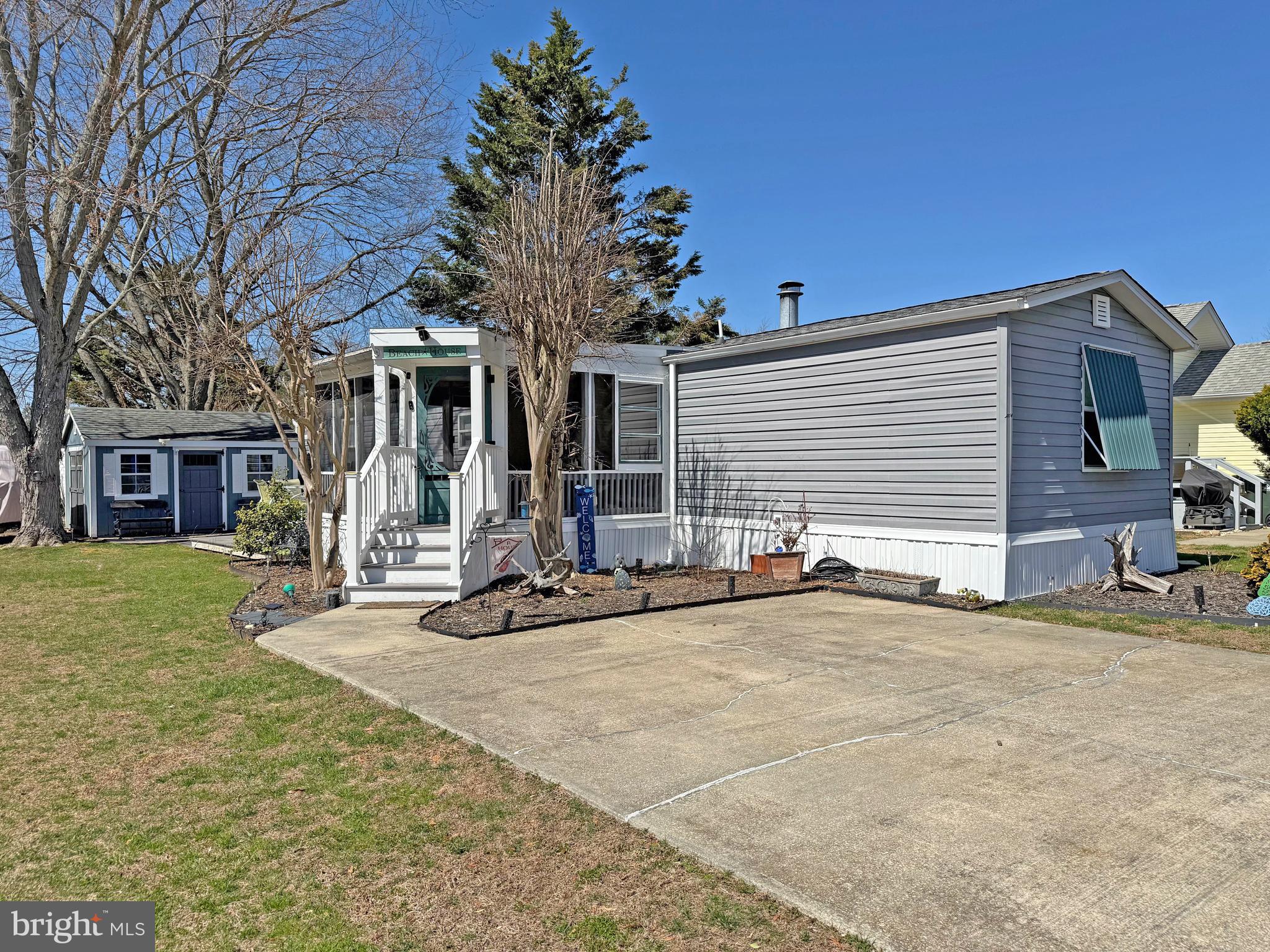 This home was nicely remodeled in 2019 & it is just 6.5 miles to the famous Rehoboth boardwalk…but why leave the community when the amenities include a bayfront pool, tennis courts, playgrounds, a sandy beach, crabbing pier, boat slips (for rent), a community boat ramp & more. The home’s living room features an electric fireplace & vaulted ceilings to make that room feel extra spacious. Newer flooring & fixtures throughout. The eat-in kitchen adjoins the living room. It has space for a dinette set & there is a breakfast bar for casual dining. The kitchen has granite countertops, a tile backsplash & stainless steel appliances. There is a fridge with ice maker, smooth-top electric range, built-in microwave, dishwasher & a disposal. The main bedroom is to the rear of the home. It has an elegant en Suite bath, which includes a contemporary double-sink vanity, lighted mirror, a large tiled shower with a multi-spray shower head, towel warmer rack & a cedar-lined linen closet. The main bedroom uses the double closet in the hall and the walk-in closet in the bedroom for clothes. The walk-in closet also houses the stack washer & dryer. The second bedroom is at the front of the home. The second full bath is near bedroom #2, so that bedroom feels like a suite, too. That bath has a step-in shower and an antique dry sink that’s been converted to a sink vanity. Great outdoor living spaces include a big screened porch (with custom vinyl panels), a boardwalk-style deck, and a small paver patio area in front the shed. The shed has electric, so you can charge your golf cart! The community allows 2 pets (no fences, though). Leasehold Interest: Lot Rent of approx. $744.29/mt. includes water service & trash/recycle. This Lease renews annually on January 1.  Homeowner pays electric, sewer, cable/Internet, lawn maintenance & there’s a nominal fee for pool passes. Hometown America, the community owner, requires an Application from the Buyer (and all adult occupants 18-year-of-age or older), with acceptance based on the following criteria: 1.)income verification, 2.)credit bureau score, plus evaluation of debt-to-income ratio, and 3.)criminal background check. No short-term rentals, but rental of 6 months or longer may be allowed with Park Management approval. Financing may be available to qualified borrowers from only a few Lenders that specialize in installment/chattel loans for manufactured homes on leased land. Closing costs will include 3.75% DMV Doc Fee & Settlement Agent fee.