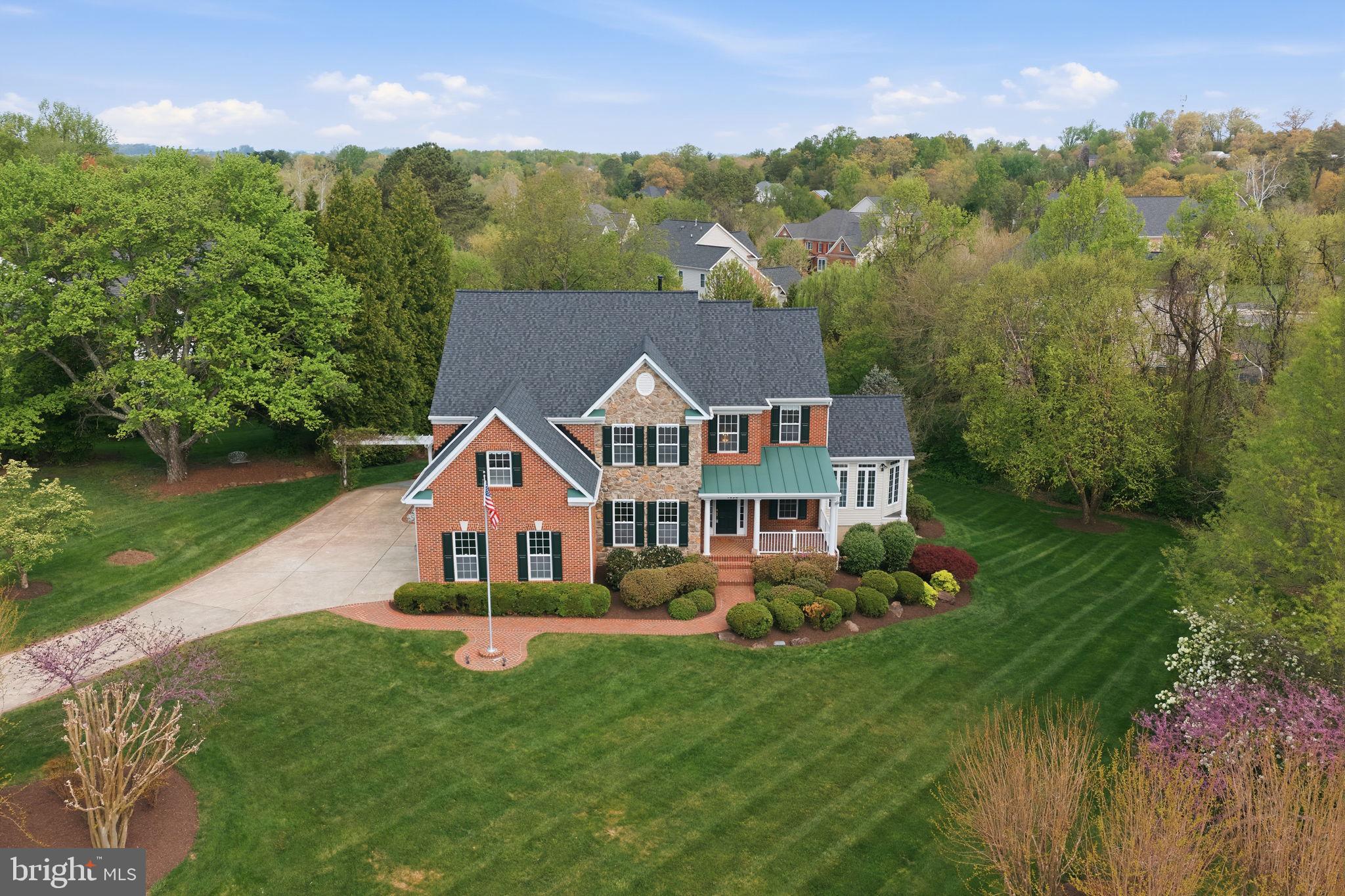 Discover refined living in this exceptional 5-bedroom, 4.5-bath residence, ideally positioned on a private 0.85-acre lot in the prestigious Stuart Estates community. Blending timeless elegance with modern comfort, this light-filled home offers a thoughtfully designed layout ideal for both everyday living and sophisticated entertaining. The main level features formal living and dining rooms, alongside a dramatic two-story family room highlighted by a striking fireplace that anchors the home. The well-appointed kitchen offers abundant cabinetry, generous counter space, and a sunlit breakfast area featuring a Tiffany lamp that creates a warm and inviting start to the day. Just beyond, a wall of windows in the sunroom provides a peaceful retreat with serene views of the lush backyard and beautiful sunsets. A convenient rough-in for a second laundry room on the main level adds valuable flexibility for future customization. Upstairs, the spacious primary suite serves as a true sanctuary, complete with walk-in closets, a spa-inspired bath designed for relaxation, and a private laundry room for added convenience. A secondary bedroom with a private en-suite bath adds comfort and privacy, while additional generously sized bedrooms share a well-maintained hall bath, offering flexibility for guests, work from home needs, or daily living. The finished basement adds approximately 2,100 square feet of versatile living space, complemented by an additional 400 square feet of unfinished storage. The lower level also includes a beautifully remodeled bathroom, making it ideal for recreation, guests, or multi-generational living. Designed for versatility, the home includes multiple living spaces that easily adapt to your lifestyle, whether gathering, working, or unwinding. Outdoor living truly shines with an expansive deck, complete with an electronic retractable awning for effortless shade. Just beyond, a spacious patio overlooks a beautifully landscaped, private backyard that's perfect for enjoying breathtaking sunsets. A professionally installed irrigation system keeps the grounds lush with minimal upkeep, while a recirculating stream cascades over natural stone into a serene pond, creating a peaceful and visually captivating water feature. Recent upgrades include a 2 year old roof, a whole-house generator, and a leaf guard gutter system, offering reliable comfort and peace of mind year-round. Andersen French doors provide seamless walkout access to both the deck and the basement. The three-car side-load garage further adds convenience and curb appeal. Perfectly located near downtown Herndon and Reston Town Center, with easy access to major commuter routes, shopping, dining, Metro, and Washington Dulles International Airport, this home offers a rare combination of estate style space, modern convenience, and a prime Northern Virginia location.