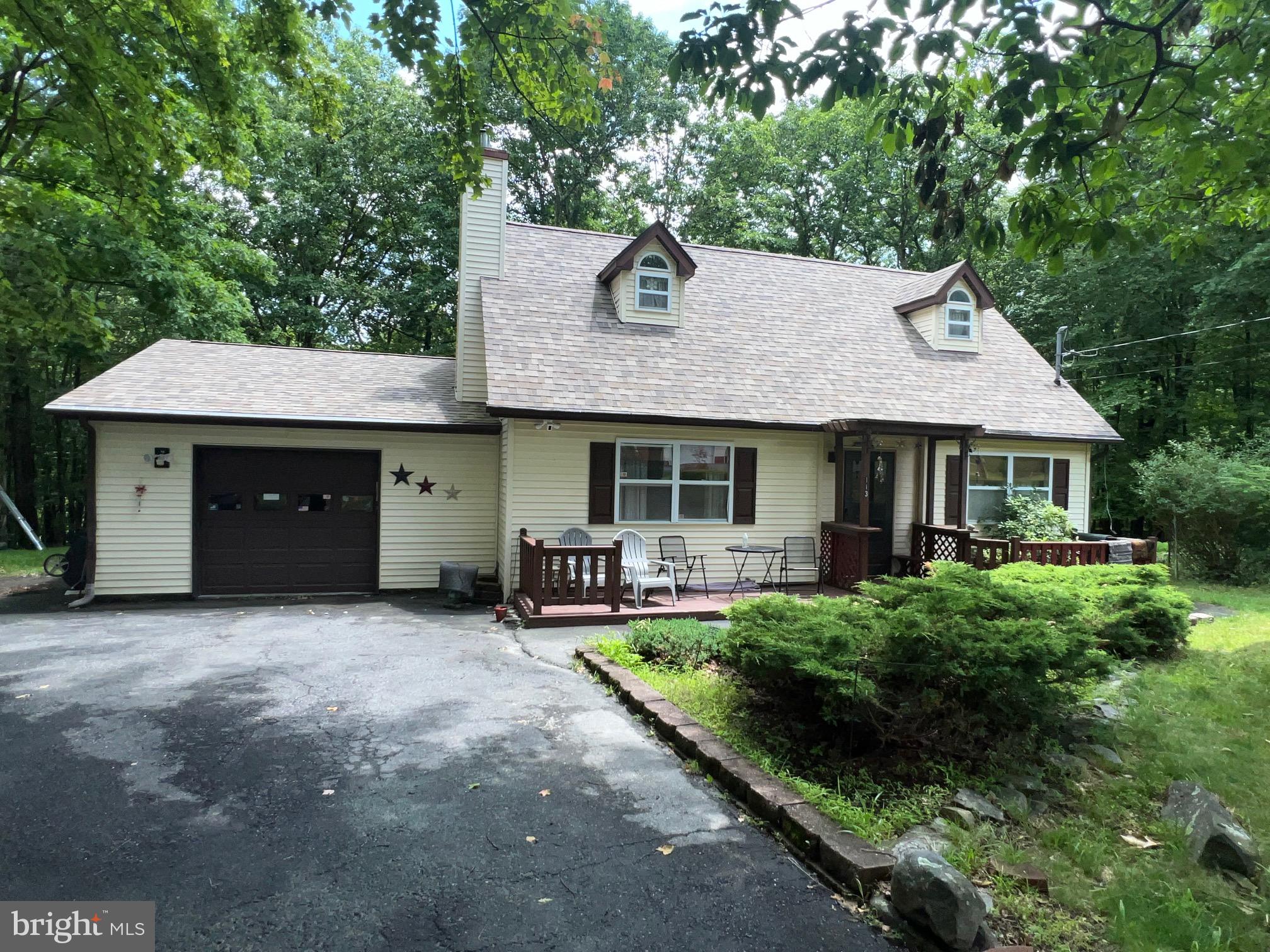 Welcome to the perfect blend of Pocono Country Living and only 90 MINUTES FROM NYC. Are you looking for privacy? This well maintained 3 BR, 1.5 BA which includes a primary bedroom on the main level and a cozy wood burning stove in the living room welcomes you to comfort. This lovely home is situated nicely from the street on a level lot. The backyard is very private, providing a peaceful retreat, and a flat paved driveway offers easy parking. The garage has a built-in work bench. Community offers pool, playground, pond, lake, security, road maintenance and more. Conveniently located near fishing, boating, and the famous Bushkill Falls which is perfect for nature lovers and outdoor enthusiasts. HOME WARRANTY INCLUDED!