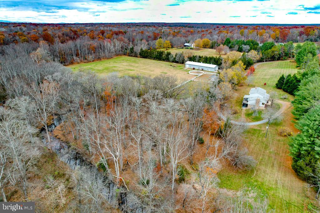 PRICED BELOW RECENT APPRAISAL - INSTANT EQUITY!! Offered for the first time in nearly 20 years, this 24.61-acre equestrian and recreational property in the heart of Spotsylvania County offers privacy and convenience in an unbelievable setting. The 3,000+ sqft home features 4 bedrooms, a formal dining room, a formal living room, and one additional room in the basement that could serve as an extra bedroom—each with access to a full bath. The large primary bedroom boasts an en-suite full bath with his and her closets. The walkout basement offers abundant space for a workshop, gym, or recreation area. There are 3 fireplaces in the home with a combination of wood and gas. A whole-house generator with a buried propane tank can help you weather the storm! Equestrian enthusiasts will appreciate the 5-stall horse barn (2 horse ready with 3 stalls requiring finishing touches - graded w/stone & floor padding stored onsite) with conditioned tack and washroom, water and electricity, and approximately 12 acres already fenced with a jumping ring. A separate equipment shed provides additional storage for tractors, lawnmowers, etc. The property also features a 6,000+ sqft Morton building with a concrete floor, metal siding, 400-amp service, a roughed-in studio/office that needs completion, and a concrete bunker— with two horse stalls & additional room. Wilderness Run creek borders the west and north sides of the property, creating a private island—ideal for picnics, campfires, morning coffee, or exploring. Gold has even been found in the creek! Conveniently located just 30 minutes from Fredericksburg and major interstates, this property offers rural seclusion with easy access for commuting and amenities! All buyers must provide proof of funds or a preapproval letter. All showings must be confirmed 48-hr before showing. Listing agent will be present for all showings. BRAND NEW UPSTAIRS HIGH EFFICIENCY HVAC INSTALLED OCTOBER 2025!!!!