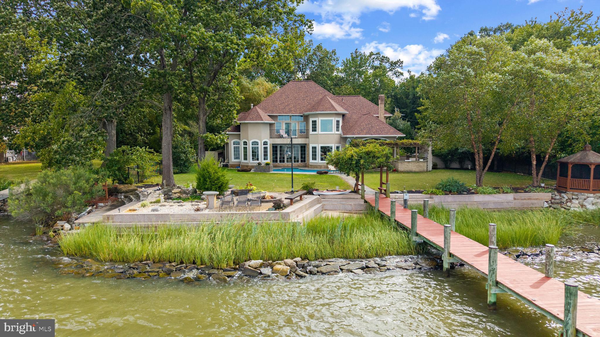 Welcome to a truly remarkable waterfront retreat where timeless design meets resort-style living. Set along the shores of Hopkins Cove with sweeping views of the West River, this residence offers over 150 feet of water frontage and a private pier stretching nearly 270 feet, complete with boat lift and covered pavilion—everything you need to embrace life on the water.

This five-bedroom, four-and-a-half-bathroom home is designed for both relaxation and entertaining. The indoor and outdoor living spaces flow seamlessly, with a backyard that feels like a private resort. Manicured gardens, a custom outdoor kitchen, and an inviting pool with hot tub create the perfect setting for gatherings large or small. From morning coffee as the sun rises to evenings spent watching the sky glow at sunset, every day here feels like a getaway.

Inside, the attention to detail is immediately apparent. A dramatic two-story foyer sets the stage with custom double doors, wrought iron railings, and striking stonework that bring warmth and sophistication. The chef’s kitchen, appointed with top-tier Viking appliances, is both functional and inspiring, while the living room’s fireplace provides a cozy vantage point to take in views of the pool and river.

The primary suite is a sanctuary of its own, offering a spacious retreat with a spa-like bath that rivals any five-star hotel. Additional bedrooms and baths provide comfort for family and guests, while custom finishes in stone, wood, and ironwork continue throughout the home, creating an atmosphere that is both refined and welcoming.

This is more than a home—it’s a lifestyle. Whether entertaining by the pool, setting out from your private pier, or simply enjoying the quiet beauty of Hopkins Cove, every detail has been designed to elevate daily living. Experience the very best of waterfront living and make this extraordinary property your own.