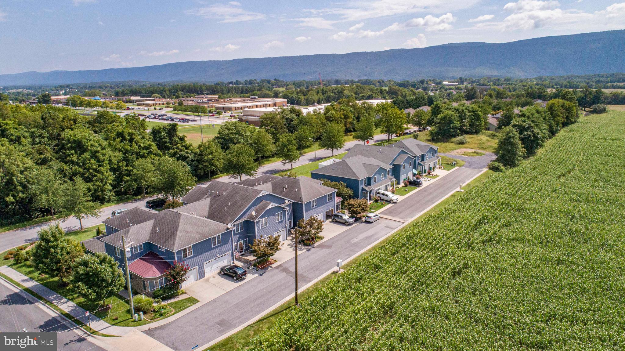 BRAND NEW TOWNHOUSES WITH  MOUNTAIN VIEWS -MODERN LIVING IN WOODSTOCK. 
*LIMITED-TIME OFFER!  CONTRACTS FULLY EXECUTED BY JULY 15, SELLER WILL CONTRIBUTE $1500 TOWARD BUYER CLOSING COSTS.  DON’T MISS THIS OPPORTUNITY TO SAVE!
Introducing 3 beautifully crafted new-construction townhomes in the heart of Woodstock, Virginia.  These two-story homes offer a unique and thoughtfully designed floor plan featuring  3 spacious bedrooms, 2.5 bathrooms, and an attached garage –offering a modern lifestyle in a scenic setting.  Step inside and immediately feel the difference.  These homes are not your typical townhome layout –wide hallways, open-concept living areas, and generous room dimensions create an exceptional sense of space.  The beautiful kitchen is a true centerpiece, featuring a large stone island with seating for four, quartz countertops, solid wood cabinetry, stainless steel appliances, and a walk-in pantry just steps away.  The open-concept design seamlessly connects the kitchen, dining and living areas –creating a natural flow ideal for both everyday living and effortless entertaining.  Whether you’re hosting friends or enjoying a quiet night in, the space feels welcoming and connected.  Upstairs, the expansive primary suite serves as a peaceful retreat, with enough space for a cozy sitting area or home office.  Enjoy an ensuite bath with double vanity, a spa-inspired walk-in shower with ceramic tile extending to the ceiling, and a walk-in closet.  Each home is built with front porches designed to enhance your enjoyment of the striking Edinburg Gap Mountain views.  Natural gas service is brought directly into every home, allowing for a gas stove and gas hot water heater –delivering efficiency, convenience and modern comfort.  Surrounded by the natural beauty of the Shenandoah Valley, you’ll enjoy easy access to the new Seven Bends State Park, local wineries, scenic hiking trails, and Shenandoah River recreations.  You’re just minutes from downtown Woodstock with its charming shops, restaurants, and small-town hospitality.  Don’t miss this opportunity to live in a vibrant and growing community, where comfort, design, and location come together effortlessly.   Please note: photographs are from a previously built townhome and are representative of style and layout.  Some images may show upgraded features not included in base pricing.