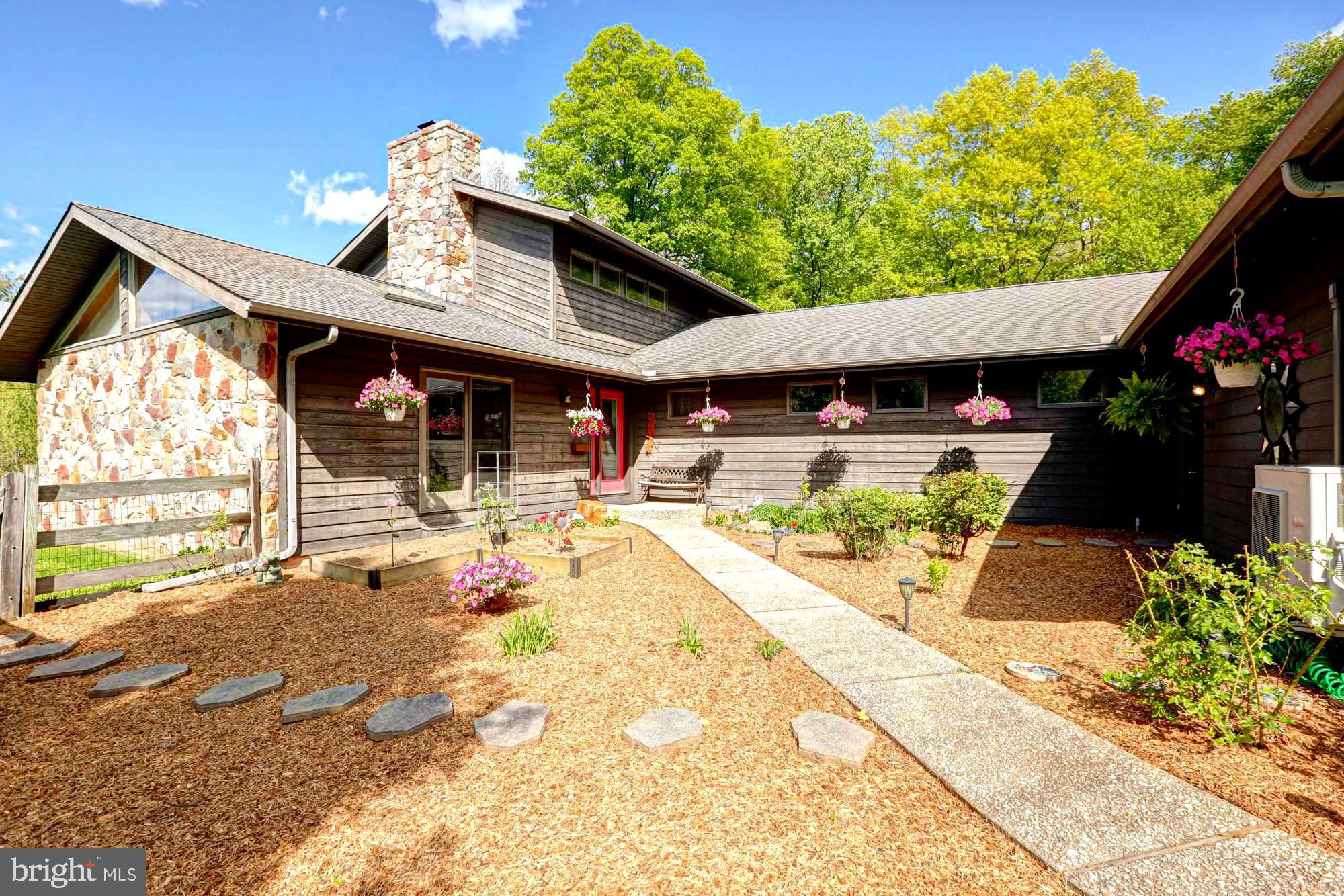 Tucked away at the end of a long, secluded lane, this striking contemporary home offers the perfect blend of privacy, space, and distinctive design. Set on 4.2 beautifully balanced acres of fenced open ground and woods with a small creek, this property is a rare opportunity to enjoy both nature and modern comfort, complete with walking trails and a serene pond featuring a fountain that can be viewed from the deck. 
The heart of the home is a spacious, light-filled kitchen featuring stainless steel appliances, a center island, exposed beams, hardwood flooring, a wet bar, a pantry, and a charming plant window. Two sets of sliders lead directly to the expansive deck-ideal for indoor-outdoor living and entertaining while overlooking the picturesque pond. A convenient pass-through window connects the kitchen to the dining room, which is highlighted by a large triple window.
The dramatic family room is a true showstopper, boasting a vaulted ceiling with skylights and a stunning stone wood-burning fireplace as its focal point. Sliders open to a small deck offering a beautiful, sweeping view of side of the the property.
The main level includes three generously sized bedrooms—each with its own slider access to the decking. A full bath located down the hall services these bedrooms, while a conveniently placed powder room (half bath) and laundry room complete the main floor.
Upstairs, the private primary suite offers a peaceful retreat with a walk-in closet, full bath, many windows, and a versatile loft space accessed through a stylish barn door. The loft features two skylights and offers excellent cross ventilation, enhanced by mechanically operated windows, making it an ideal space for a home office, gym, or relaxation area.
The walkout lower level expands the living space even further and is perfectly suited for multi-generational living. Featuring French doors that lead to a covered patio with a hot tub area as well as a concrete firepit pad. This level includes a comfortable living space, kitchenette, full bathroom, and an additional flexible room currently used as a train room. There’s also a dedicated exercise room with cork flooring, a workshop with multiple windows, and a unique bunker-style storage area. The workshop includes secondary stair access to the garage, while the primary access to the garage is located on the main level. Whole house Central Vacuum!
Car enthusiasts and hobbyists will appreciate the oversized three-car garage, complete with heating and cooling, an epoxy floor, utility sink with hot and cold water, and direct access to both the home and garden. A compressor is also included with the property. Expanded driveway parking fitting multiple vehicles as well as a 2 car carport.
Additional highlights include ceiling fans in all bedrooms, a whole house generator for peace of mind, and a charming courtyard entrance adorned with mature plantings and seasonal blooms. The house is a certified wildlife habitat. Large Shed with electric for all things outdoor. 
This one-of-a-kind property in the Avon Grove school district offers exceptional versatility, privacy, and character—an ideal setting for those seeking something truly special. Easy access to the Jennersville Shopping Center with a grocery store, restaurants and other conveniences. and Rt1. Christiana Care Hospital is just a few miles away.