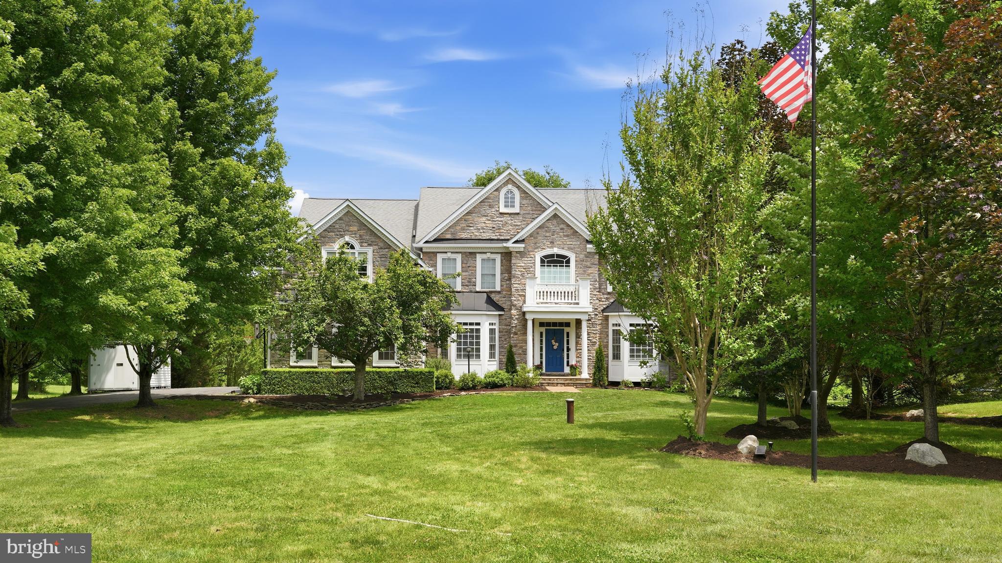 Tucked within the peaceful Willow Oaks community in Nokesville, this exceptional estate offers the rare blend buyers dream about: grand living, everyday comfort, wide-open privacy, and a location that feels worlds away while still keeping modern conveniences within reach. Set on 10 scenic acres along Cedar Run Creek, this 5-bedroom, 5 full and 1 half bath residence delivers more than 5600 total square feet of beautifully finished living space, including a fully finished walk-up lower level designed for gathering, relaxing, and entertaining with ease.

From the moment you arrive, the setting feels special. Mature trees, open land, and the natural beauty of the creekside acreage create a retreat-like atmosphere,

Inside, the home opens with a grand yet welcoming entry that immediately sets the tone. Elegant architectural details are found throughout the main level, including deep crown and chair moldings, recessed lighting, gorgeous columns, and beautiful built-ins that bring warmth and character to the home’s impressive scale. Formal living and dining rooms provide polished spaces for holidays and special occasions, while a private home office offers a quiet place to work, read, or manage the day.

At the heart of the home, the family room makes a stunning statement with its floor-to-ceiling stone fireplace, creating a space that feels both dramatic and deeply comfortable. Open to the gourmet kitchen, this area is designed for real life — the kind of place where everyone naturally gathers. The kitchen features a large center island with pendant lighting, abundant cabinetry, upgraded finishes, large windows overlooking the rear grounds, and a bright breakfast area that invites lingering a little longer. Whether hosting a crowd or enjoying a quiet evening at home, this main level offers the perfect balance of elegance and ease.

Upstairs, the grand primary suite feels like its own private sanctuary. Complete with an electric fireplace, sitting room,  walk-in closets, and ensuite bath, it offers the space and serenity buyers crave at the end of the day. Four additional secondary bedrooms are also located on this level, each light-filled and generously sized. With three additional full baths upstairs, the layout is beautifully suited for busy mornings, overnight guests, or anyone who appreciates room to spread out without stepping on each other’s toes.

The fully finished walk-up lower level expands the home’s possibilities even further. Movie nights feel right at home in the media room, game nights have plenty of space in the recreation area, and the additional full bath adds convenience for guests, extended stays, or entertaining. With walk-up stairs leading directly to the backyard, this level connects seamlessly to the outdoor setting and makes it easy to enjoy every inch of the property.

Outside, the large rear deck is the perfect vantage point for taking in the beauty of the land with a backdrop that feels peaceful, private, and endlessly inviting. Just below, the pool adds an entirely new layer of enjoyment, creating the perfect setting for sun-filled afternoons, weekend cookouts, and pool parties. Add in a 3-car garage, three finished levels, generous room sizes, and a setting that feels like a private retreat, and this home becomes so much more than a place to just live.  For buyers seeking space, privacy, natural beauty, and a home that is ready to welcome them in, this Willow Oaks property is a rare opportunity.

This home also offers impressive energy-conscious upgrades that make everyday living even more appealing.  A 15-kilowatt solar panel system helps significantly reduce utility costs, while the upgraded geothermal heat pump provides efficient heating and cooling year-round.  An EV charging station adds another modern convenience, making the property as forward-thinking as it is beautiful.  It is the perfect blend of grand country living, thoughtful efficiency, and practical luxury,