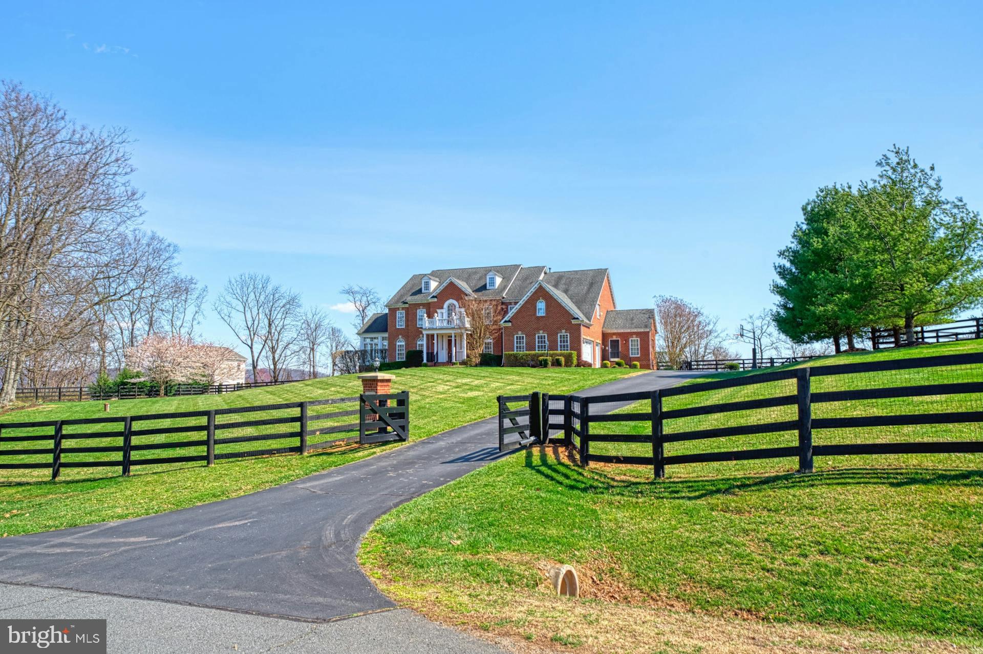 Elegant with chic farmhouse interiors and high-end craftsmanship, this distinctive home with endless accommodation simply impresses, while 3.01 fence-wrapped and gated acres boast sweeping hilltop-views. From gently sloping grounds, leading to professionally laid flowering landscapes, you’ll arrive to the care of your three car garage - complete with custom flooring and electric car-charger - then enter to find well over 8,270  square feet inviting with shiplap-clad detailing, hardwoods, refined moldings, coffered ceilings, elegant fixtures, and incredible sun-filled windows. In your superb provincial-style kitchen, restful sophistication feels luxurious as guests, settled in the sitting space, adore sites of your sun-lit breakfast room-windows and cottage-perfect exposed beams. Here, pour wines for celebrations, plan weeknight meals, and fill the home with savory aromas utilizing professional-grade appliances, glazed cabinetry, and a walk-in-pantry for showcasing favorite serveware. As views of the endless deck, turquoise pool, and rolling hillsides inspire lingering long after summer-parties have ended, little loved ones will enjoy the play set as you prep firepit-fun for sunset conversation.  With a hearth-warmed living room, lower-level wet bar, home theater, inviting gym, sunroom, spacious laundry, and place to close deals, you’ll move through the day’s needs with ease before six generously sized bedrooms - each with private baths - care for dreaming.  Host guests in the lower level suite, then recover in the primary where a spa-like bathroom and bespoke closet allow you to unwind the day.  While on tour, visit the posh mudroom hall, and imagine life’s picture-perfect moments captured on the imperial staircase.  From home, discover why seasonal and 4th of July firework views - from the Highlands’ highest peaks - are a local favorite vantagepoint, and enjoy ease to historic townships, wineries, parks, and nearness to business and entertainment destinations via Route 7.