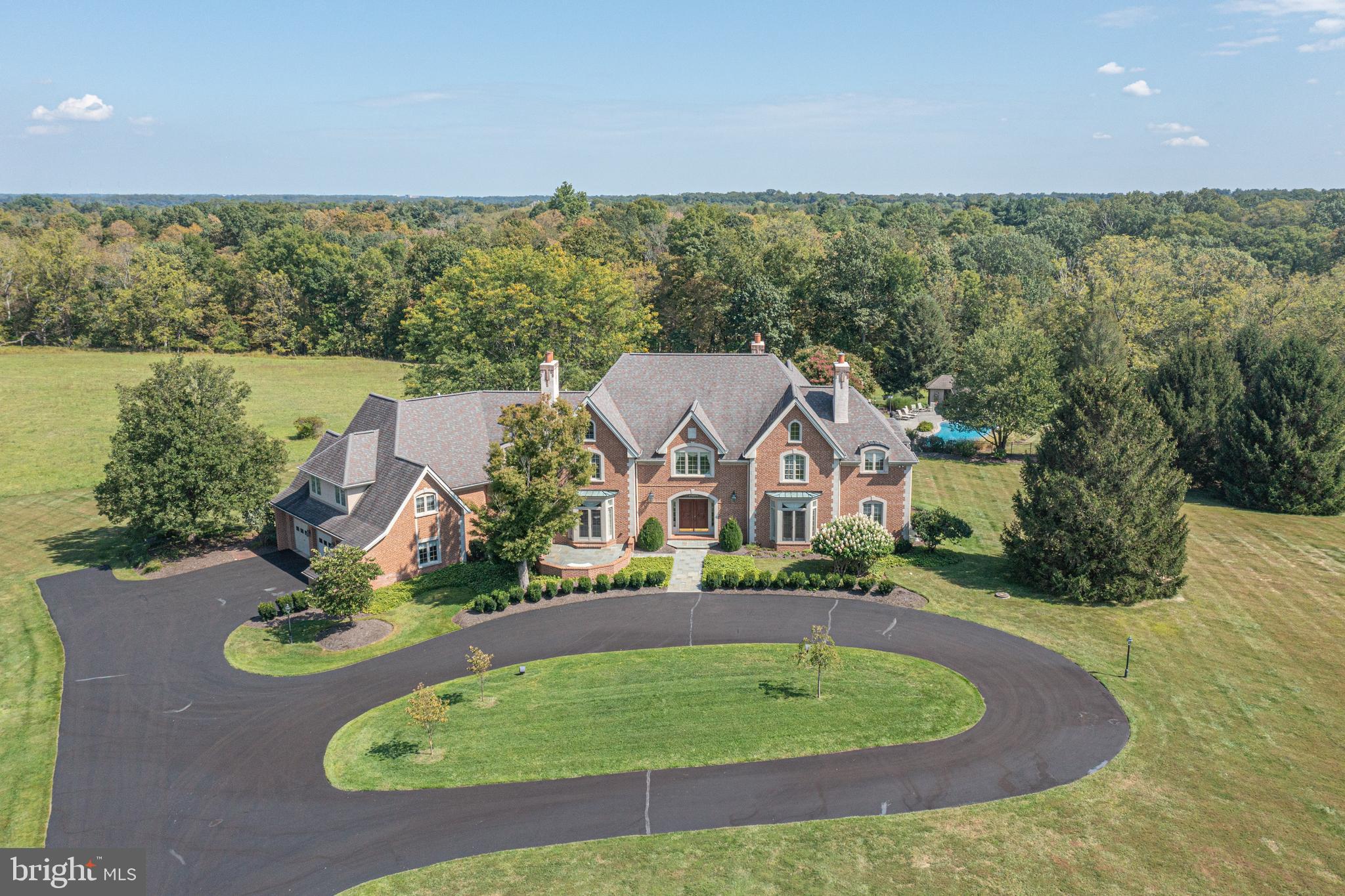 Tucked at the end of a private cul-de-sac within an exclusive enclave of just ten estate homes, this magnificent all-brick manor set on 10 acres is a rare offering of grand scale, timeless architecture, and refined living.  A sweeping circular driveway sets the stage for an impressive arrival, leading to a stately home designed for both elegant entertaining and comfortable everyday living. A welcoming two-story foyer with a dramatic circular staircase creates an unforgettable first impression. Flanking the entrance, the formal living room and elegant dining rooms, both with fireplaces, offer beautifully proportioned spaces for hosting gatherings and special occasions.  Toward the rear of the home, a richly paneled library with a fireplace creates a distinguished home office, offering access to a private outdoor terrace—perfect for quiet moments or working from home in style. Just beyond, the sunken family room features a wood-burning fireplace and provides a warm, inviting gathering space, flowing seamlessly into the gourmet kitchen with a large center island and abundant workspace. The nearby sunken breakfast room is wrapped in walls of windows that frame picturesque views of the backyard and surrounding gardens, filling the space with natural light.  For colder evenings, the gas fireplace creates a warm and inviting atmosphere, adding both charm and character to the room.  Designed with entertaining in mind and adjacent to the kitchen, the home features a true butler’s area with ample cabinetry, secondary appliances and entertaining essentials.  Completing the first floor is an oversized laundry room, half bath and a mudroom, situated in close proximity to the entrance to the three-car garage.  Designed with both luxury and functionality in mind, the home features 8 spacious bedrooms and 7.2 bathrooms, arranged across two staircases, including a private au-pair wing and a first-floor in-law suite, ideal for extended family or guests.  Upstairs, the master bedroom suite is thoughtfully situated in its own wing of the home, offering a peaceful retreat from the main living areas. This spacious sanctuary features a comfortable sitting room, perfect for relaxing with a book or enjoying quiet moments at the end of the day. Dual walk-in closets provide generous storage, while the luxurious en-suite bath is appointed with a soaking tub, double vanities, and ample space for everyday comfort and convenience.  Additionally, a finished third floor offers flexible space ideal for a children’s playroom, home gym, or additional storage.  The expansive basement offers the best of both worlds, with one half fully finished as a recreation room featuring a built-in bar, fireplace, a media area, pool table, game room, and full bath, while the remaining half remains unfinished, providing abundant storage or the opportunity for future customization.  Outdoor living is equally impressive, with multiple flagstone patio areas designed for dining and relaxation, an in-ground pool with attached spa, and a pool house that enhances both convenience and resort-style living. These outdoor spaces create a seamless extension of the home, perfect for summer entertaining and private enjoyment. This exceptional residence offers a unique opportunity to own a home of remarkable craftsmanship, scale, and presence in an intimate and prestigious setting, all within the award-winning Council Rock School District!