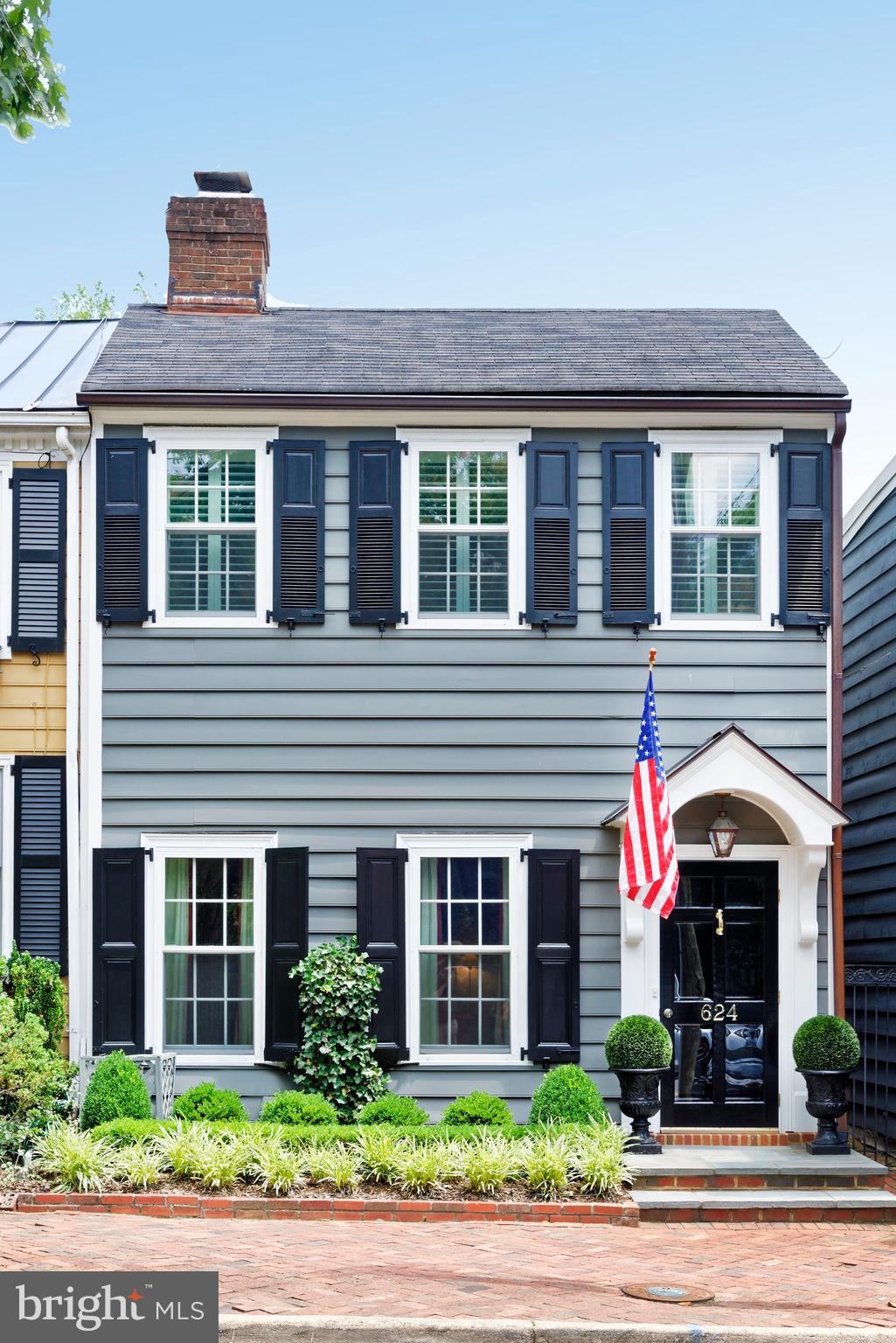Circa 1875, this semi-detached townhouse offers gracious rooms for entertaining and everyday living, a private outdoor retreat, and one off-street parking space.  The home benefited from Polly Hulfish’s preservation efforts in the 1950s and has been thoughtfully updated and meticulously maintained over the years.
The stylish living room features parquet flooring, crown molding, plantation shutters, and a gas fireplace with a marble surround and ventless gas logs.  The formal dining room offers parquet flooring and crown molding, while a striking chandelier adds warmth and elegance, creating an inviting atmosphere for entertaining.  A conveniently located powder room is finished with herringbone marble tile.
An elegant archway leads to the sun-filled breakfast room, where three skylights with new shades, built-in cabinetry, and abundant storage create a bright, functional space.  Enjoy preparing meals in the adjoining kitchen with cherry cabinetry, brick flooring, and Miele appliances.  Relaxation is effortless in the first-floor family room adjacent to the kitchen.  Anchored by a wood-burning fireplace with new venting, architectural details including decorative paneling and custom bookshelves lend timeless character.
A graceful double staircase with volutes, rake balusters, and a wool runner leads to the upper level.  Handsome matching bell jar light fixtures accent the staircase at both the top and bottom.  A lovely primary suite is a peaceful retreat offering hardwood floors, plantation shutters, and a new Daikin mini-split system.  The en-suite bath includes a seamless glass shower, skylight, and additional storage.  Two generously sized guest bedrooms, one with a custom built-in desk, share a Jack-and-Jill bath with a skylight. 
A delightful surprise, the unique rooftop deck offers a private escape above the Old Town rooftops.  Unwind with a favorite drink as the sun sets, relax in comfort, or enjoy a good book as you slow down and take in the peaceful surroundings.
Savor the outdoors or dine al fresco on the beautifully landscaped patio oasis graced by a pergola, climbing wisteria, gardenia, and lush greenery.  A new brick wall and gate provide access to the off-street parking space for one small car.  Situated on one of Old Town’s most sought-after streets, this historic beauty is just minutes from interesting shops, wonderful restaurants, gourmet food stores, the river, and the Mount Vernon Trail.