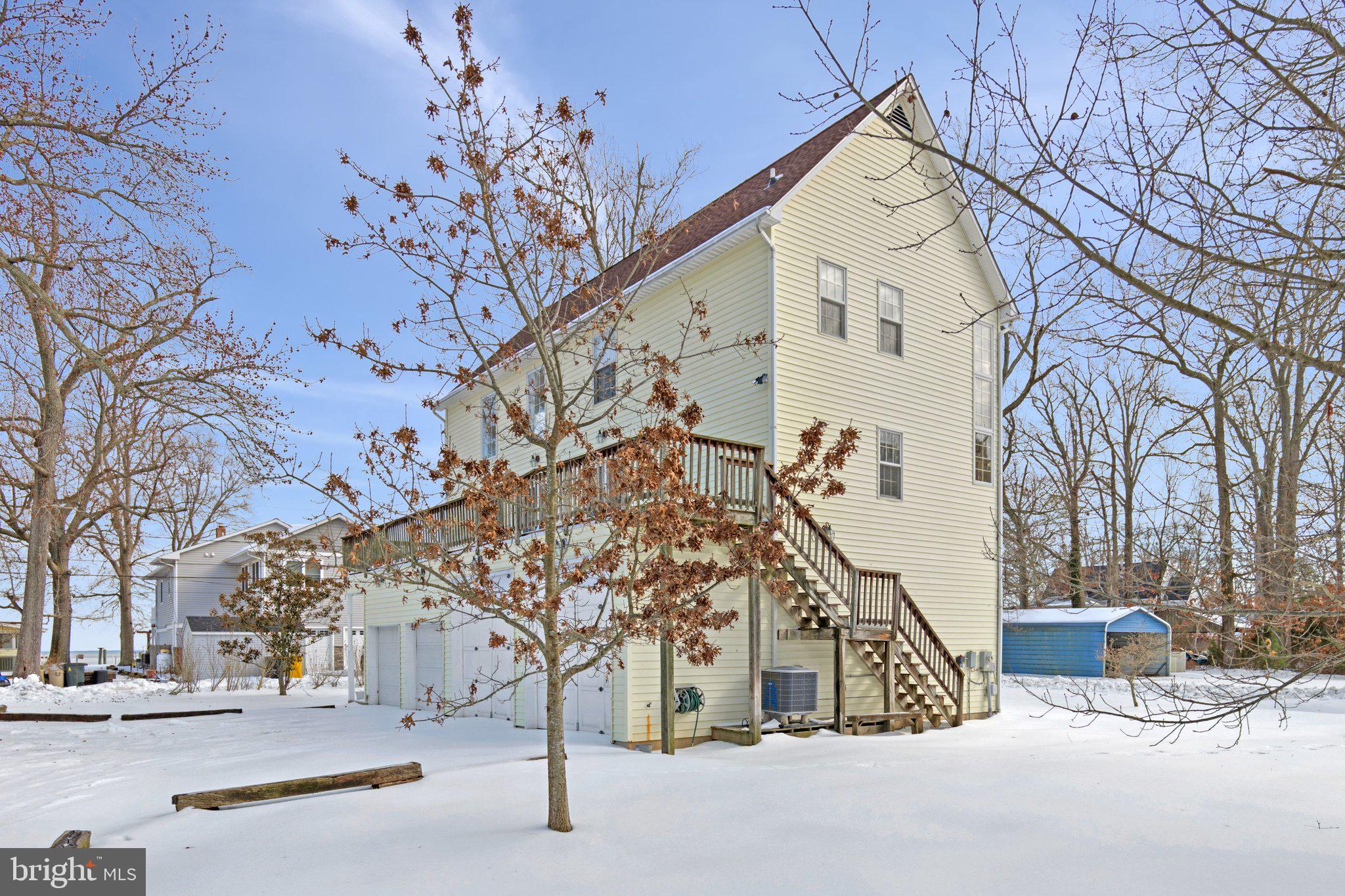 An utterly singular waterside retreat — part boathouse, part sky-high great room, entirely unlike anything else on the Chesapeake.
Some properties defy easy description. 850 Walnut Avenue is one of them. Positioned just steps from the Chesapeake Bay and moments from the Herrington Club and the charming shops and restaurants of downtown North Beach, this idiosyncratic residence turns the traditional home concept on its head — literally and figuratively.
Arrive at the property and you are greeted by four drive-through garage bays at street level — two sized perfectly for boats, two for full-size vehicles — allowing you to pull straight through the base of the structure. The entire living space floats above, creating a seamless blend of coastal utility and architectural drama that simply cannot be replicated.
Step through the front door and ascend a full flight of hardwood stairs into one of the most breathtaking great rooms in the region. Soaring 20-foot ceilingsdraw the eye upward while an abundance of windows floods the space with natural light from every angle. Suspended ceiling fans circulate the bay breeze year-round, and a classic wood-burning stove anchors the room with warmth and character on cooler evenings.
The main level is thoughtfully appointed with generous cabinetry, a panel-front refrigerator, dishwasher, and microwave, a dedicated dining area, powder room, and ample storage throughout. Step outside onto the large deck — an ideal perch for sunrise coffee or sunset entertaining with bay air all around you.
Upstairs, two bedrooms and a full bath with tub/shower await, along with a stunning overlook down into the great room below — a vantage point that never gets old. Every level of this home offers a fresh perspective and a sense of being lifted above the ordinary.
Steps to the bay. Steps to the Herrington Club. A short stroll to downtown North Beach. And unlike anything else on the market — this is the one you will remember.