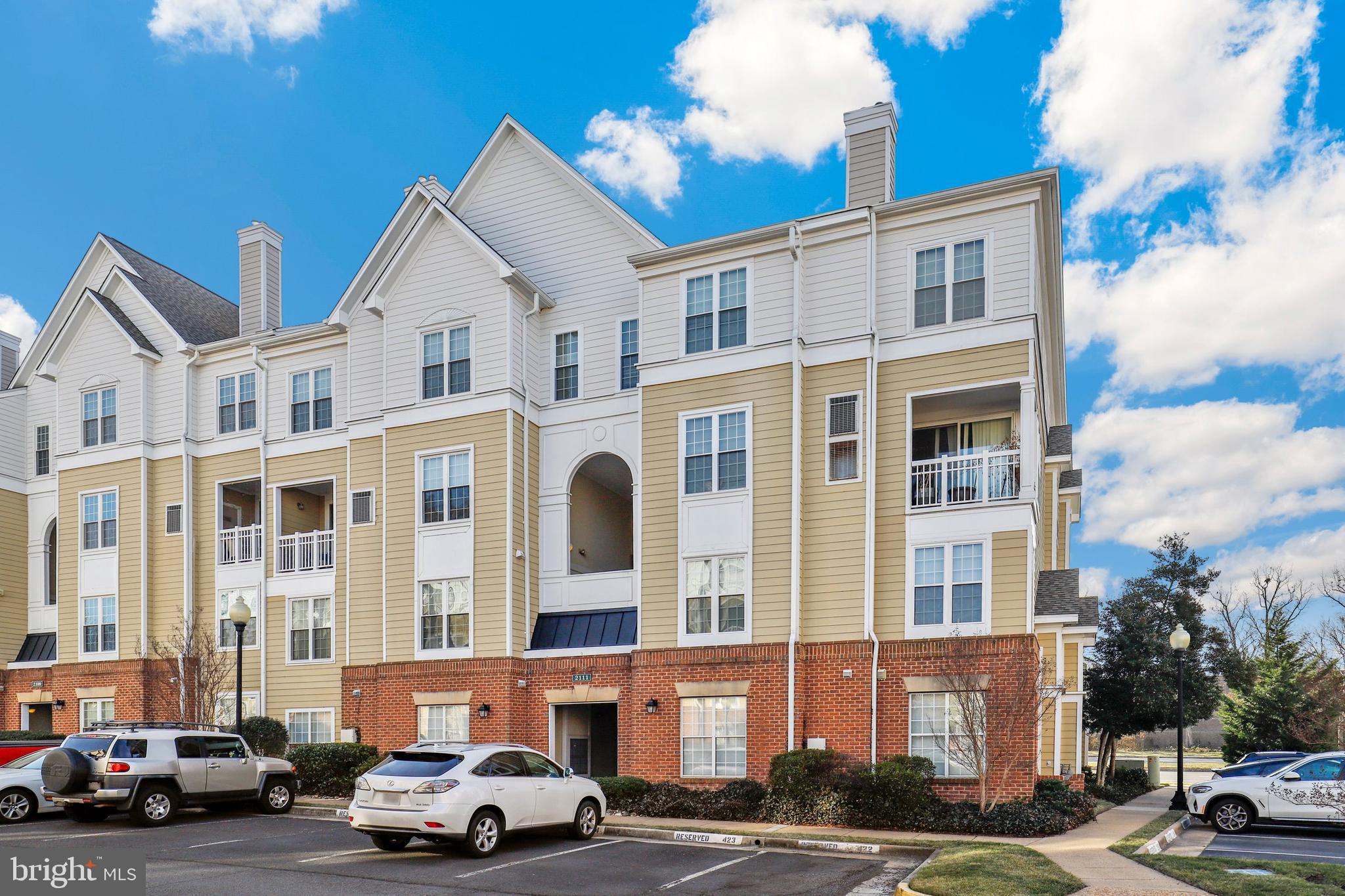 WALKING DISTANCE TO SILVER LINE METRO. Thoughtfully renovated and freshly painted, this light-filled condo blends elevated finishes with exceptional everyday functionality just moments from multiple shopping plazas.  Recent upgrades include hardwood flooring in both bedrooms, recessed lighting, custom closet systems, and updated baths (all 2022). The main living space is both refined and versatile, anchored by a marble-clad gas fireplace and complemented by a custom marble built-in workstation—ideal for seamless work-from-home living. The kitchen offers granite countertops, stainless steel appliances, and generous cabinetry. Additional conveniences include an in-unit washer and dryer and a private balcony with durable Trex decking. Major systems—HVAC and hot water heater—were replaced in 2022, offering long-term peace of mind. Complete with new blinds (2026), one assigned parking space, and one permit space, this home delivers a compelling combination of location, quality, and low-maintenance living.