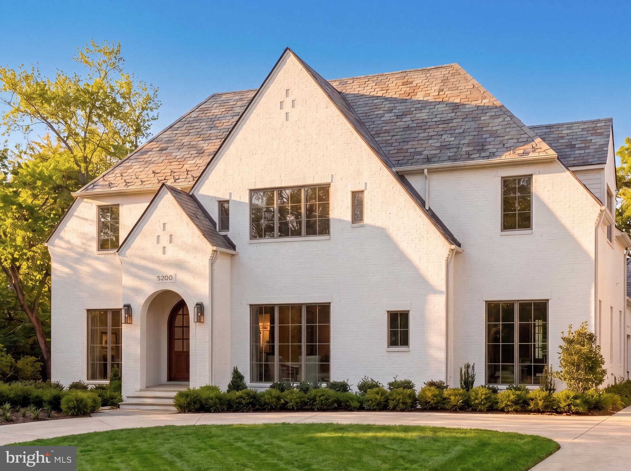 Set on a prestigious corner lot in the heart of coveted Kenwood, 5200 Dorset Avenue is the newest architectural achievement by Terra Innovations, created in collaboration with the acclaimed GTM Architects and the master craftsmen at Castlewood Builders. Conceived as a transitional Tudor, the residence is clad in crisp white brick, blending timeless English-inspired architecture with a sophisticated, contemporary aesthetic designed for modern living.

Purposefully oriented to capture southern exposure, the home is filled with natural light throughout its principal living spaces. A rare detached one-car garage complements the concealed two-car side-entry garage, maximizing both functionality and green space. A sweeping driveway leads to the stately façade, where steeply pitched gables, a slate-style roof, and a custom arched mahogany-and-glass entry door create a striking first impression. Inside, a subtly vaulted foyer introduces 8,808 finished square feet thoughtfully arranged across four levels.

A classic center-hall floor plan defines the main level. The formal living room is bright and welcoming, while the dining room is distinguished by a tray ceiling with cove lighting, creating an elegant setting for entertaining. A private study with custom built-ins and access to a full bath offers exceptional flexibility, easily serving as a main-level guest suite.

The open-concept family room is the heart of the home, where dramatic ceiling beams, custom built-ins, and a gas fireplace create a warm yet refined atmosphere. Expansive glass doors open to a covered porch with its own fireplace, pre-wired for screens, heaters, and media, seamlessly extending the living space outdoors.

The chef's kitchen is centered around a handcrafted 9-foot artisan island and appointed with bespoke millwork, luxurious stone finishes, and premium hardware. A striking 55-inch Lacanche Classique range is paired with a state of the art appliance suite,  while a concealed coffee bar, butler's pantry, and sunlit breakfast area enhance both everyday living and entertaining. A thoughtfully designed mudroom wing includes a powder room, pantry, laundry hookup, and direct garage access.

The upper level is anchored by a luxurious primary suite featuring a sitting area, private terrace, and dual custom walk-in closets. Its spa-inspired bath offers heated floors, a freestanding soaking tub, dual vanities, and a Kohler digital shower. Four additional en-suite bedrooms and a spacious laundry room complete the level, while the top floor provides an additional bedroom, full bath, and family room—all serviced by the home's four-level elevator.

Designed for both recreation and relaxation, the lower level centers around a 32-foot recreation room with a wet bar and glass-enclosed wine display. Wellness amenities include a fitness studio, sauna, and steam shower, while a pre-wired golf simulator bay with raised ceilings offers flexibility as a recreation, media, or sports lounge. A private au pair suite with exterior access completes the level.

Outside, the private rear lawn is already equipped with pool-ready infrastructure, offering endless possibilities for future outdoor living. Perfectly positioned among Kenwood's iconic cherry blossoms, directly across from the revitalized Westbard Square, and just minutes from Downtown Bethesda, top-rated schools, and major commuter routes, the location is as exceptional as the home itself.

A remarkable expression of design, craftsmanship, and modern luxury, 5200 Dorset Avenue represents one of Kenwood's finest new construction offerings and a rare opportunity in one of the Capital Region's most coveted neighborhoods.