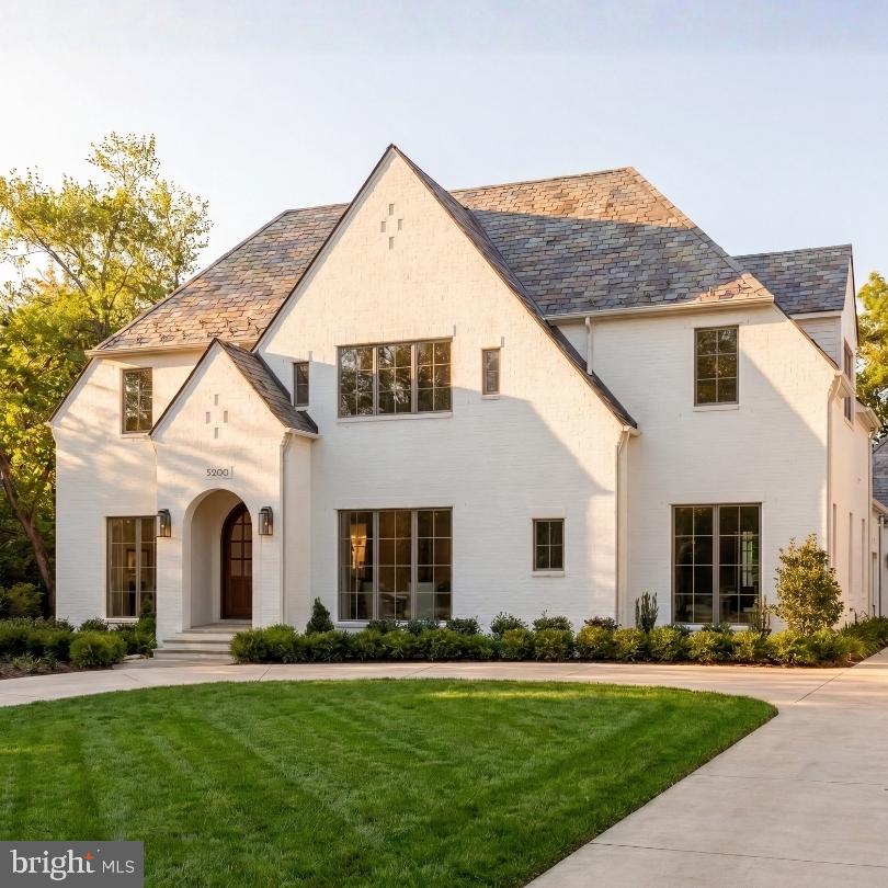 Set on a prestigious corner lot in the heart of coveted Kenwood, 5200 Dorset Avenue is the newest architectural achievement by Terra Innovations, created in collaboration with the acclaimed GTM Architects and the master craftsmen at Castlewood Builders. Conceived as a transitional Tudor, the residence is clad in crisp white brick, blending timeless English-inspired architecture with a sophisticated, contemporary aesthetic designed for modern living.

Purposefully oriented to capture southern exposure, the home is filled with natural light throughout its principal living spaces. A rare detached one-car garage complements the concealed two-car side-entry garage, maximizing both functionality and green space. A sweeping driveway leads to the stately façade, where steeply pitched gables, a slate-style roof, and a custom arched mahogany-and-glass entry door create a striking first impression. Inside, a subtly vaulted foyer introduces 8,808 finished square feet thoughtfully arranged across four levels.

A classic center-hall floor plan defines the main level. The formal living room is bright and welcoming, while the dining room is distinguished by a tray ceiling with cove lighting, creating an elegant setting for entertaining. A private study with custom built-ins and access to a full bath offers exceptional flexibility, easily serving as a main-level guest suite.

The open-concept family room is the heart of the home, where dramatic ceiling beams, custom built-ins, and a gas fireplace create a warm yet refined atmosphere. Expansive glass doors open to a covered porch with its own fireplace, pre-wired for screens, heaters, and media, seamlessly extending the living space outdoors.

The chef's kitchen is centered around a handcrafted 9-foot artisan island and appointed with bespoke millwork, luxurious stone finishes, and premium hardware. A striking 55-inch Lacanche Classique range is paired with a state of the art appliance suite,  while a concealed coffee bar, butler's pantry, and sunlit breakfast area enhance both everyday living and entertaining. A thoughtfully designed mudroom wing includes a powder room, pantry, laundry hookup, and direct garage access.

The upper level is anchored by a luxurious primary suite featuring a sitting area, private terrace, and dual custom walk-in closets. Its spa-inspired bath offers heated floors, a freestanding soaking tub, dual vanities, and a Kohler digital shower. Four additional en-suite bedrooms and a spacious laundry room complete the level, while the top floor provides an additional bedroom, full bath, and family room—all serviced by the home's four-level elevator.

Designed for both recreation and relaxation, the lower level centers around a 32-foot recreation room with a wet bar and glass-enclosed wine display. Wellness amenities include a fitness studio, sauna, and steam shower, while a pre-wired golf simulator bay with raised ceilings offers flexibility as a recreation, media, or sports lounge. A private au pair suite with exterior access completes the level.

Outside, the private rear lawn is already equipped with pool-ready infrastructure, offering endless possibilities for future outdoor living. Perfectly positioned among Kenwood's iconic cherry blossoms, directly across from the revitalized Westbard Square, and just minutes from Downtown Bethesda, top-rated schools, and major commuter routes, the location is as exceptional as the home itself.

A remarkable expression of design, craftsmanship, and modern luxury, 5200 Dorset Avenue represents one of Kenwood's finest new construction offerings and a rare opportunity in one of the Capital Region's most coveted neighborhoods.