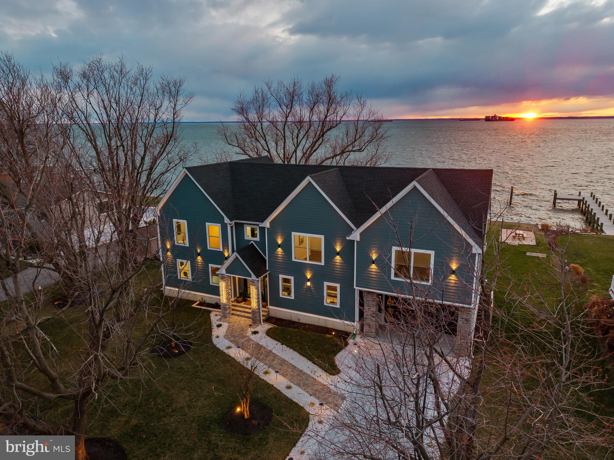 Designed by YSA Homes and Simply Wesley Interior Design of Annapolis, this extraordinary brand-new modern coastal farmhouse style smart-home offers over 6,148 square feet of thoughtfully designed living space, where every tile throughout the home was handpicked and expertly curated using top-of-the-line luxury selections. The kitchen is outfitted with premium, top-tier appliances including Wolf, creating a seamless blend of elevated craftsmanship, timeless design, and modern functionality at every turn. The property is permitted for a pool to be built. This stunning residence features five oversized bedrooms, each with its own expansive en suite bathroom, and three of the five have waterfront bay views. Totals include six full bathrooms, two half bathrooms, five gigantic bedrooms, 2 car oversized attached garage with rear entry door. An owner’s suite on the main level (with huge custom closet) provides everyday convenience, while the second level includes an additional  owner’s suite with a massive custom walk-in closet, ideal for multi-generational living or extended guest stays. Upon entering the home, you are welcomed into an open-concept main level where the kitchen flows seamlessly into the dining and living areas, creating an ideal setting for entertaining and everyday living. The living room is anchored by a striking wireless water vapor fireplace, offering modern ambiance without heat or emissions. A main-level half bath adds convenience, while the primary suite features a spa-inspired oversized bathroom with a soaking tub, a large European-style walk-in shower, and exquisite designer finishes throughout. The second level impresses with a spacious great room, complete with a wet bar and an additional half bath, opening to a large upper-level deck designed for optimal water views and entertaining. Four generously sized en suite bedrooms are located on this level, two of which showcase stunning water views through oversized windows, filling the space with natural light. The lower level offers exceptional flexibility, featuring a walk-out basement with exterior sliding doors, a full bathroom, a dedicated laundry room, and ample space for a game room, den, home gym, or additional living areas. Ask the listing agent about available improvement and build-out options for the basement. Outdoor living continues on the main-level patio, with the option to expand or customize to suit your vision. Located on sought-after Kent Island, this home offers access to a true Chesapeake Bay lifestyle just approximately 20 minutes from historic downtown Annapolis. Enjoy nearby waterfront parks, marinas, beaches, and miles of scenic walking and biking trails along the Cross Island Trail. Golf enthusiasts will appreciate proximity to Blue Heron Golf Course with membership options available, as well as the nationally recognized Queenstown Harbor Golf Links featuring two championship courses. Residents can easily enjoy all that downtown Annapolis has to offer, including boutique shopping, waterfront dining, sailing culture, festivals, and the charm of the historic district and U.S. Naval Academy. Just minutes away, **Queenstown Premium Outlets—featuring Calvin Klein, J.Crew, and other popular brand-name retailers—*provide convenient access to everyday shopping. Kent Island is also home to waterfront dining, local crab houses, and Love Point Vineyards, while Terrapin Nature Park and Matapeake Beach offer stunning Chesapeake Bay views. Conveniently positioned for commuting to Baltimore and Washington, D.C., this location blends coastal living with everyday accessibility. This is not just a home, this is a coastal lifestyle.