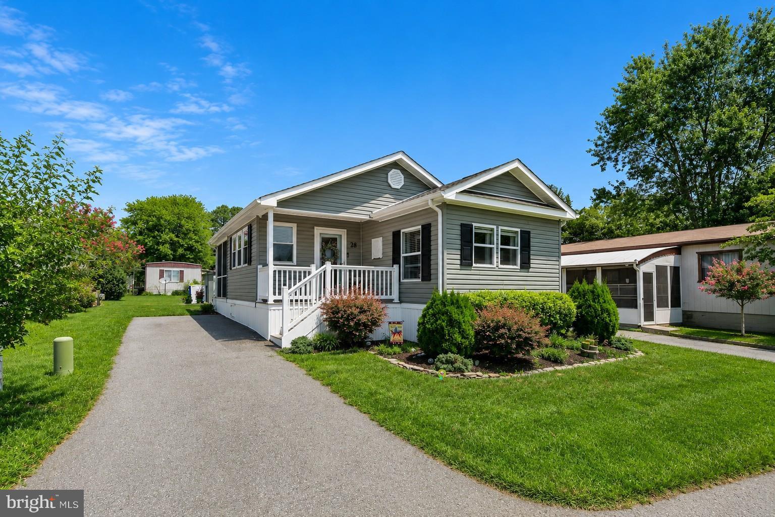 Welcome to 28 Wagon Wheel Lane in Colonial East Mobile Home Park, where thoughtful updates, comfortable living spaces, and an exceptional location come together. Beautifully renovated in 2020 and meticulously maintained, this inviting home offers stylish finishes, abundant natural light, and a desirable split-bedroom floor plan with private bedroom suites positioned on opposite ends of the home. Adding to its appeal, the home is being sold partially furnished, providing a convenient opportunity to move in and begin enjoying your new coastal lifestyle right away.

A welcoming front porch sets the stage before stepping inside to find luxury vinyl plank flooring throughout the main living areas and a bright, open interior. The spacious sunroom features a vaulted ceiling, its own energy-efficient mini-split system, and a pocket door that provides flexibility between the sunroom and the main living space. Sliding glass doors lead to a relaxing screened porch, creating the perfect setting for morning coffee or evening gatherings.

The living room showcases modern décor, an in-ceiling speaker system, and a charming wood-burning brick fireplace with a substantial wood mantel that serves as the heart of the home. The adjoining dining area offers built-in cabinetry and shelving, adding both character and convenient storage. The updated kitchen combines style and function with white cabinetry accented by elegant gold hardware, abundant cabinet storage, a wide sink beneath a window, and stainless steel appliances that were replaced during the 2020 renovation.

The spacious primary suite features two closets and a beautifully updated private bath complete with a large soaking tub, separate shower, and contemporary fixtures. On the opposite side of the home, the second bedroom enjoys access to an updated Jack-and-Jill bath and includes a built-in desk and shelving, making it ideal for guests, a home office, or hobby space.

Outside, the landscaped yard provides attractive curb appeal and includes a convenient storage shed for gardening tools and seasonal items. For added peace of mind, the current owner recently had the home professionally re-leveled in April 2026 and completed flooring repairs. Land rent includes an impressive collection of amenities and services, including a community pool, dog park, playground, lawn maintenance, trash service, and snow removal.

Ideally located, Colonial East places you just minutes from the Midway Movies, fitness centers, miniature golf, shopping, restaurants, and everyday conveniences. The scenic Junction & Breakwater Trail is approximately one-half mile away, offering an easy bike ride to downtown Rehoboth Beach, while nearby public transportation provides even greater accessibility.