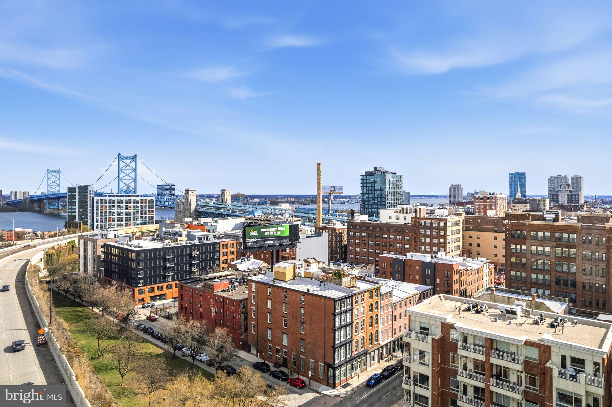 This beautifully updated penthouse offers a unique blend of historic character, modern comfort, and stunning views of the Delaware River and Ben Franklin Bridge. Filled with natural light from oversized windows, the open-concept layout creates an easy flow between the living, dining, and kitchen areas—ideal for both everyday living and entertaining.

Original details like exposed brick and a decorative fireplace are paired with thoughtful updates, including refinished hardwood floors and custom built-ins that add warmth and functionality throughout. The kitchen is both stylish and practical, featuring a Sub-Zero refrigerator and Miele dishwasher, self-cleaning, dual convection oven, five-burner range,  custom cherry cabinetry, and leathered granite countertops.

The primary suite provides a comfortable retreat with a walk-in closet, in-unit washer/dryer, and a spacious bath with marble finishes, dual sinks, and an oversized shower. A second bedroom and full bath offer flexibility for guests, a home office, or additional living space.

One of the standout features is the private, furnished roof deck—an inviting outdoor space with sweeping views of the Ben Franklin Bridge and Delaware River. With built-in seating, planters, and lighting, it’s perfect for relaxing or hosting friends.  Additional highlights include low condo fees, updated HVAC, a restored roof deck, a newly replaced elevator, and freshly painted interiors.

Located in the heart of Old City, just steps from popular restaurants, cafes, galleries, and historic landmarks, with green spaces and open areas a few blocks away, plus a pocket park directly across the street.  A rare opportunity to enjoy penthouse living with character, outdoor space, and iconic views in one of Philadelphia’s most desirable neighborhoods.