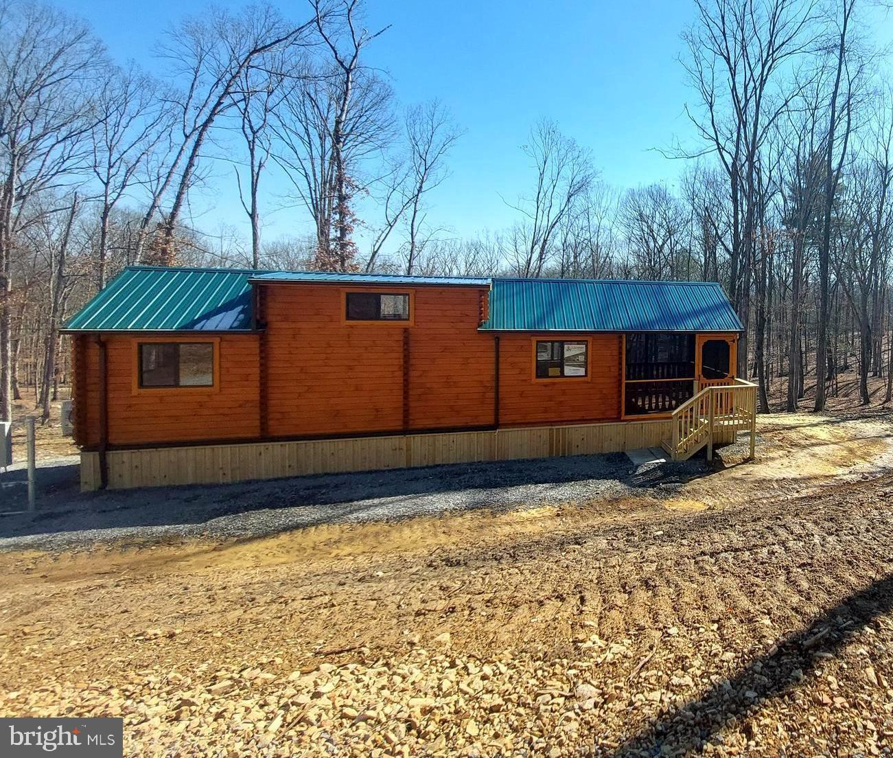 Introducing a charming, manufactured log cabin nestled in the South Potomac Forest Subdivision of West Virginia. This cozy retreat spans 400 square feet, representing the essence of small space living while offering ample comfort and functionality.  As you approach, you're greeted by a welcoming 12-foot enclosed porch, perfect for enjoying morning coffee or evening sunsets in the wooded mountain surroundings.   A great additional living space that can be enjoyed year round!  Step inside to discover a thoughtfully designed interior featuring a spacious living area, adorned with rustic accents and lots of natural light.  Head up the stairs to the loft area where accommodations large enough for two queen sleepers can be found!  A comfortable space for guests or relaxation. The main floor boasts a primary bedroom for peaceful nights' rest, alongside a bunk room ideal for accommodating additional visitors or creating a cozy nook area for office space or storage/pantry/linen.  A full bath ensures convenience, complete with modern amenities. Meanwhile, the functional galley kitchen boasts efficient appliances and ample storage, for preparing meals with ease.  Situated on 2.5 acres, this retreat offers the perfect blend of seclusion and recreation. Residents can unwind by the great pond, enjoying catch-and-release fishing or leisurely picnics in the shaded picnic area.  For outdoor enthusiasts, the cabin's proximity to the South Branch of the Potomac River provides endless opportunities for adventure, with public access for fishing, kayaking, and floating less than a mile away.  Embrace the simplicity of country living and reduce your budget without sacrificing comfort. Whether you seek a weekend getaway or invest as a short-term rental property.  This brand-new cabin invites you to enjoy the quiet charm and natural beauty West Virginia has to offer.