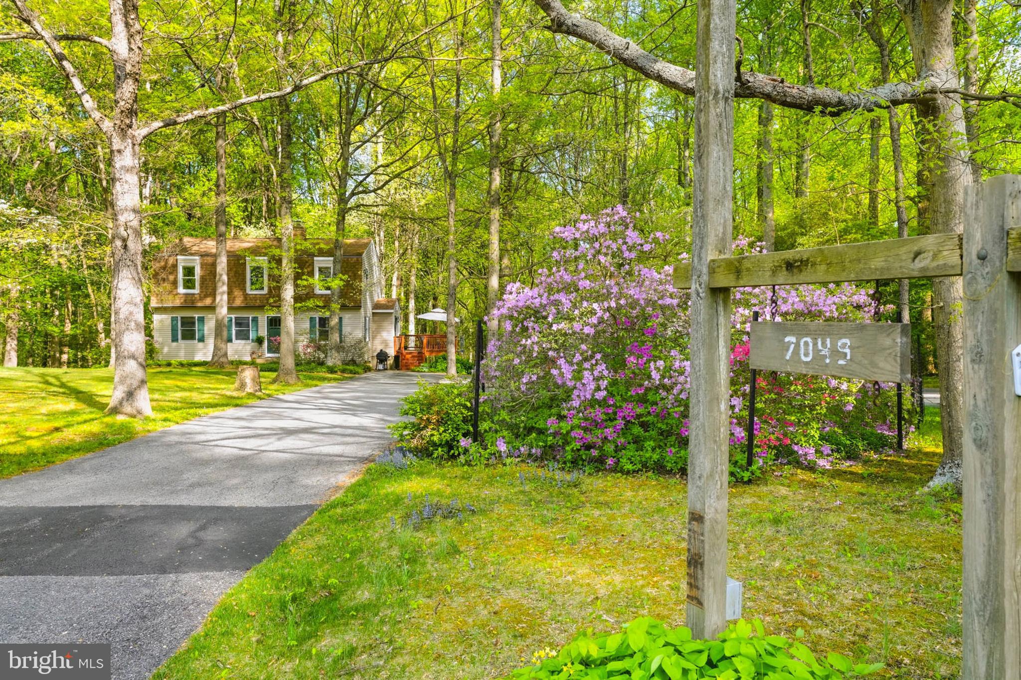 Welcome Home to 7049 Mink Hollow Rd, a beautifully maintained home by longtime owners on one of the largest and most private lots within the coveted River Hill school district!  VA transferable loan at 3.25% interest rate! The home features nearly 3,000 finished square feet of living space, 5 bedrooms and 3.5 baths sitting on over 7 acres of unbelievable wooded privacy.  Enjoy the peaceful surroundings of home as you are completely immersed in the quiet of nature as far as the eye can see.  Stunning Azaleas, climbing hydrangeas, pachysandra, hostas and hellebores gracefully surround the home as you enter via the circular driveway.  Two established fire pit areas, basketball, tetherball and regulation horseshoe pits allow for endless hours of outdoor recreation and entertaining options without leaving your yard!  A rustic detached 2-car garage features a mechanic's bay, second wood-burning stove, 220V electric installed, and three levels (garage attic and basement) for tons of storage, or even the potential to create an accessory dwelling unit.  Inside the home, you'll love the hardwood floors throughout the main and upper levels.  The main level features a sun-drenched eat-in kitchen with updated appliances, corian counters, gas cooking, two ceiling fans and under cabinet lighting.  Step into the cozy den with wood-burning fireplace and wall-to-wall custom bookshelves.  Gleaming hardwoods continue into the living room and formal dining rooms, with large windows highlighting the greenery all around you from every room.  Upstairs are four generously-sized bedrooms, including a master with two closets (one a large walk-in) and en suite bath with built in shelving on one wall.   The lower level features an enormous 5th bedroom, bonus room (currently a home gym), laundry room and half bath.  You can also enter the lower level via the mudroom conveniently right next to the outdoor shower found at the rear of the house!  Behind the house, experience the true magic of living on a secluded 7.09 acres of woods with features including a natural spring, two creeks that empty into the nearby Patuxent River, two tree stands and well-maintained driveable paths that take you all the way to the back edges of the property.  Hurry to see this one before it's gone!