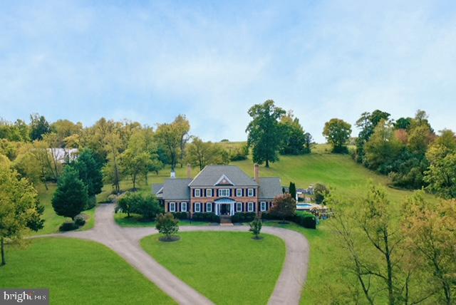 This extraordinary 5-bedroom, 6-bathroom estate sits on 14.44 acres across two parcels—5.0 acres on the front lot and 9.44 acres with the residence—just minutes from Winchester, Virginia. Designed for both everyday living and elegant entertaining, this home combines timeless style with modern luxury. Inside, hardwood floors and soaring ceilings enhance open, light-filled spaces. The recently renovated kitchen is a chef's dream, featuring a 48-inch Wolf gas range with six burners and infrared griddle, GE Monogram appliances including a pebble ice maker, and a striking quartz waterfall island with coordinating backsplash. Throughout the home, Visual Comfort chandeliers, recessed lighting, and brass Emtek hardware add refinement, while radiant floor heating on the first level ensures year-round comfort. A private gym, spacious bedrooms, and a serene primary suite elevate everyday living. All bathrooms have been updated within the last four years and now feature quartz vanity countertops. This property is made for all seasons, with three indoor fireplaces, four outdoor stone fireplaces, and a heated pool with hot tub. Expansive stone and concrete hardscaping, a hardwired exterior sound system, and professional landscape lighting create an inviting backdrop for entertaining. Practical updates include a new HVAC system (2021), a new septic system (2022), and a custom Aegis Technologies security system with exterior cameras. An attached 3-car garage plus a detached 3-car garage provide abundant parking and storage. Located just 8 minutes from Winchester Medical Center and downtown Winchester shopping, dining, and commuter routes, this home offers the perfect balance of seclusion and convenience. Don't miss the opportunity to own one of Winchester's most distinctive properties!