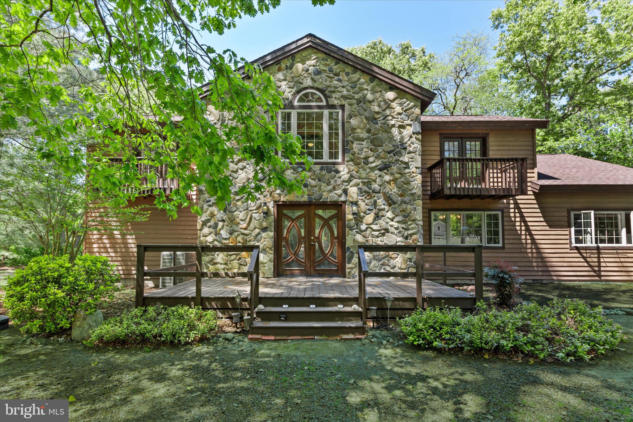 Introducing 13 Water Street, a truly special cedar and stone retreat tucked away on .65 acres along the edge of picturesque Clendaniel Pond, a protected 33-acre former millpond rich with natural beauty and wildlife. Every season brings its own magic to this peaceful freshwater setting. Spend your mornings watching eagles swoop down to fish, industrious beavers at work along the shoreline, and the occasional river otter gliding through the water, As evening falls, the gentle chorus of frogs fills the air while a symphony of birds welcomes each new day. This is more than a home; it is a private sanctuary immersed in nature!  

Surrounded by mature trees, the home’s rustic charm is immediately evident with its cedar and stone façade, side-entry garage, and impressive double-door entry. Step inside and your eyes are instantly drawn through the home to breathtaking pond views framed by the wooded backyard beyond. Beautiful plank hardwood flooring flows throughout the living spaces, while two striking stone fireplaces add warmth and character, one anchoring the living room and another creating a cozy retreat within the primary suite.

The living room is flooded with natural light from a dramatic palladium window and a wall of glass doors that lead to the expansive wraparound deck overlooking the pond. The spacious kitchen blends rustic character with modern convenience, featuring granite countertops, stainless steel appliances, a gas cooktop, wall convection oven, wood-beamed ceilings, and a casual dining area perfect for everyday gatherings. Just beyond, a more formal dining space is wrapped in windows that invite the outdoors in, while tile flooring in the kitchen offers ease of care.

Tucked behind the kitchen is an impressive family room with soaring cathedral ceilings and endless flexibility. Generously sized, this space can easily accommodate both a comfortable family room and a dedicated home office area. Added in 2019, the sunroom offers front-row seats to the tranquil pond and surrounding wildlife, creating the perfect space to unwind year-round.
The main-level primary suite is a peaceful escape complete with its own stone fireplace, deep walk-in closet, en suite bath, and direct access to the wraparound deck where serene pond views await. Upstairs, two additional bedrooms each feature walk-in closets and private Juliette balconies, offering charming personal retreats. A hall bath with a soaking tub completes the upper level.

The side-entry garage is complemented by an expansive driveway offering plenty of parking for guests and everyday convenience. Thoughtfully designed for ease of accessibility, the home features no steps from the garage into the interior living space, along with extra-wide passage doors throughout portions of the home, creating comfortable flow and added functionality for a variety of lifestyles.

Outside, the property continues to impress with a storage shed, fenced backyard area ideal for keeping pets safe, and thoughtful conveniences including central vacuum with attachments, an electronic doggie door, and an electronic pet collar that conveys with the home. Every detail of this one-of-a-kind property has been designed to embrace comfort, nature, and the beauty of waterfront living.