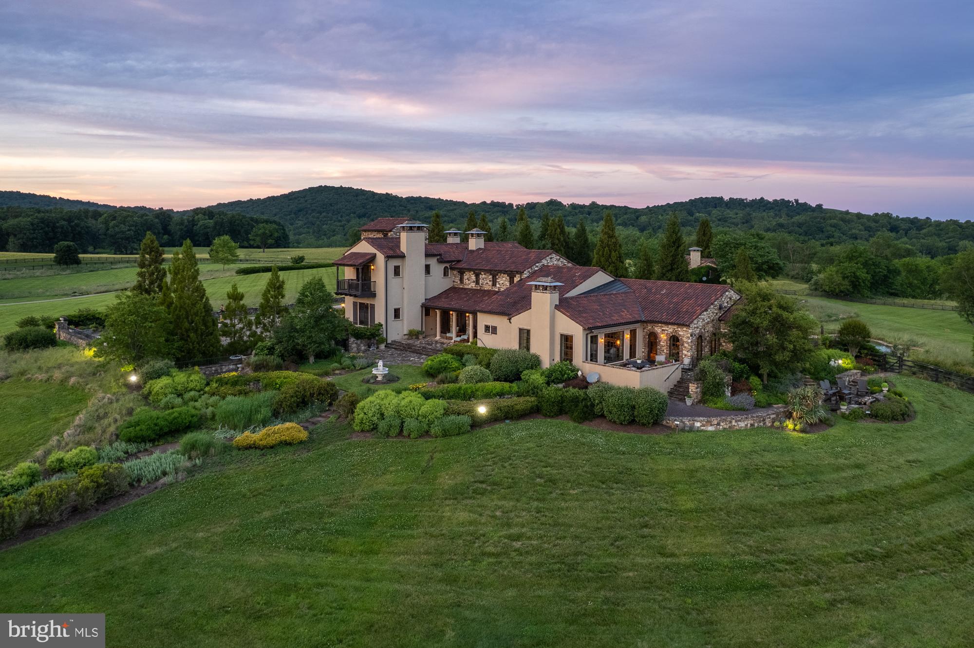 Piccola Toscana | Elegantly designed Italian Tuscan villa where rustic charm meets refined country estate living. Defined by earthy tones, natural materials, and seamless indoor-outdoor connections, this extraordinary residence was thoughtfully created to exist in harmony with its surrounding landscape.
Set amidst the breathtaking rolling countryside of Delaplane, the property embraces its natural setting through extensive landscaping, gardens, hardscaping, and carefully designed outdoor living spaces. Authentic materials are featured throughout, including terracotta tiles, stone walls, wrought iron accents, exposed timber beams, and richly textured plaster finishes, creating a timeless sense of warmth and character.
The main residence offers exceptional architectural detail at every turn, highlighted by five gas fireplaces, a gracious formal dining room, a wine room, an enclosed porch, and a luxurious primary suite conveniently located on the main level. Expansive windows frame picturesque views of the surrounding gardens and rolling hills, while outdoor patios, fire pits, and walking paths extend the living experience into nature.
Complementing the main residence is a separate guest house, a welcoming heated pool, and an outdoor lounge designed for relaxation and entertainment. At the lower end of the property, an additional detached garage has been creatively transformed into a nostalgic retro diner, providing a unique gathering space for family and friends.
Property is surrounded by the scenic Virginia countryside and enrolled in land use, seller not responsible for roll-back taxes.