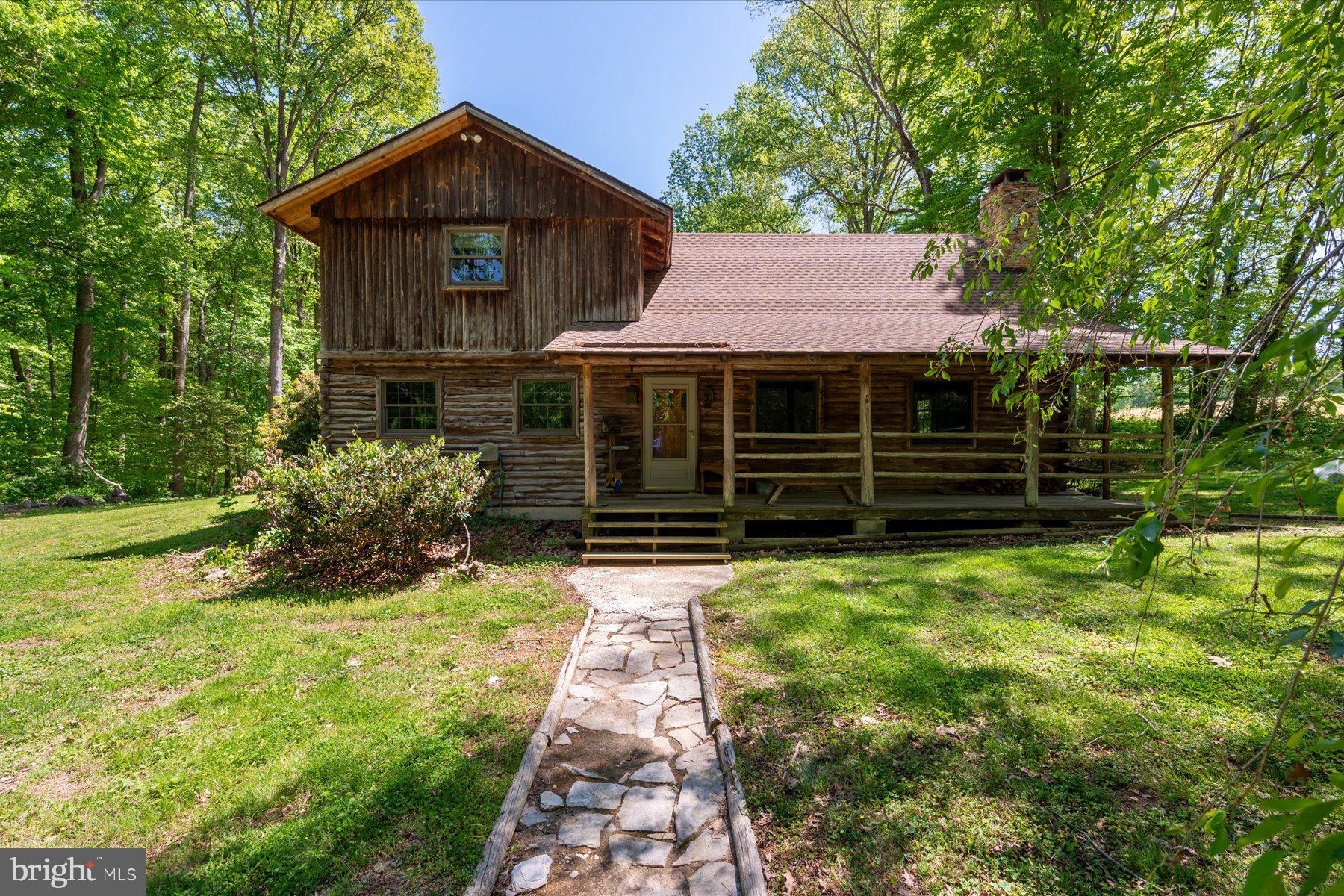 Tucked into 6.46 acres in Lothian, this custom built log cabin offers space and long term ownership pride. Crafted with exposed beams and soaring ceilings, the home centers around a large living room with a fireplace.  The layout includes three bedrooms and two full bathrooms. One bedroom is located on the main level with an attached full bath and spacious closet. The laundry room is also located on the main floor.

A two car garage provides everyday practicality, while a detached accessory building, currently outfitted with a hot tub, offers additional flexible space.  Set back from the road, the property offers a private setting while remaining convenient to Route 4. Nearby access to marinas, waterfront dining, garden centers, and shopping in Edgewater adds to the appeal, with Annapolis and Washington, D.C. also within reach.