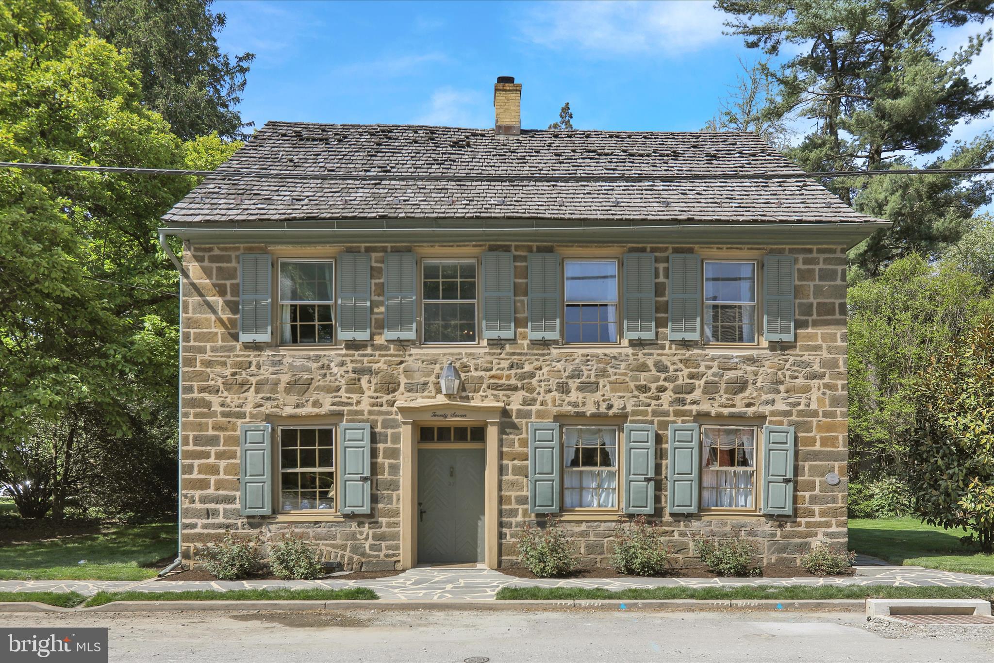 A Rare Architectural Treasure Circa 1754
Gracefully standing along one of the most admired stretches of historic Strasburg, 27 E. Main Street is a residence of extraordinary provenance, authenticity, and enduring beauty. Constructed in 1754, this remarkable stone home is among the Borough’s most cherished architectural landmarks—a property that embodies the craftsmanship, permanence, and quiet elegance of early Lancaster County.
From the moment one approaches the home, its historic significance is unmistakable. The timeless stone façade, weathered with dignity over centuries, offers a rare glimpse into America’s architectural past. Crossing the threshold into the gracious center hall is an experience unto itself—an immersion into a world where artisanship reigned supreme and every detail was crafted with intention and care.
Throughout the residence, authentic period elements remain beautifully intact. Wide-plank floors worn smooth by generations, deep-set windowsills exceeding one foot in depth, original moldings, and many historic window panes still displaying their delicate bubbles and imperfections speak to the home’s remarkable preservation. The warmth and texture found here cannot be replicated; they can only be inherited.
The first floor unfolds as a series of richly layered living spaces, each possessing its own character and sense of intimacy. The inviting family room, anchored by a fireplace, offers a warm and relaxed setting for everyday living. A distinguished library, lined with extensive built-in bookcases, evokes the atmosphere of a private study from another era, while the elegant parlor provides an ideal retreat for a home office, music room, or formal sitting area.
At the heart of the home, the formal dining room stands as a true centerpiece—gracious in scale and framed by an extraordinary walk-in fireplace that recalls the gatherings and celebrations of centuries past. This is a room designed not simply for dining, but for meaningful occasions and memorable evenings shared with family and guests.
The kitchen masterfully balances historic character with modern practicality. Rich wood flooring, and deep windows create an atmosphere of warmth and authenticity, while carefully integrated conveniences allow the home to function beautifully for contemporary living. Nearby, a thoughtfully updated laundry room and guest powder room add comfort without compromising the integrity of the residence.
Upstairs, the second floor offers four spacious bedrooms and an updated bath. The primary bedroom opens onto a charming balcony overlooking what can only be described as an enchanting landscape—a tapestry of flowering gardens, mature trees, and seasonal color that transforms the grounds into a private sanctuary.
Above, the third-floor attic reveals a breathtaking display of early craftsmanship, with exposed hand-hewn beams and gracefully curved support braces. Whether envisioned as an artist’s studio, private retreat, or additional living space, the possibilities are extraordinary.
The grounds are equally captivating. Extensive perennial gardens, a vegetable garden, and orchard create a setting of rare beauty and serenity. Built into the foundation of a former barn, the stone terrace offers an idyllic setting for outdoor entertaining, surrounded by fragrant blooms and the timeless ambiance of this historic estate.
Additional amenities include a private driveway with generous off-street parking, a detached two-car garage, and a charming barn ideal for hobbies, storage, or workshop use.
Properties of this architectural importance and authenticity seldom become available. 27 E. Main Street is more than a residence—it is a stewardship opportunity, offering the rare privilege of becoming part of Strasburg’s enduring history.
Private tours are now available by appointment.