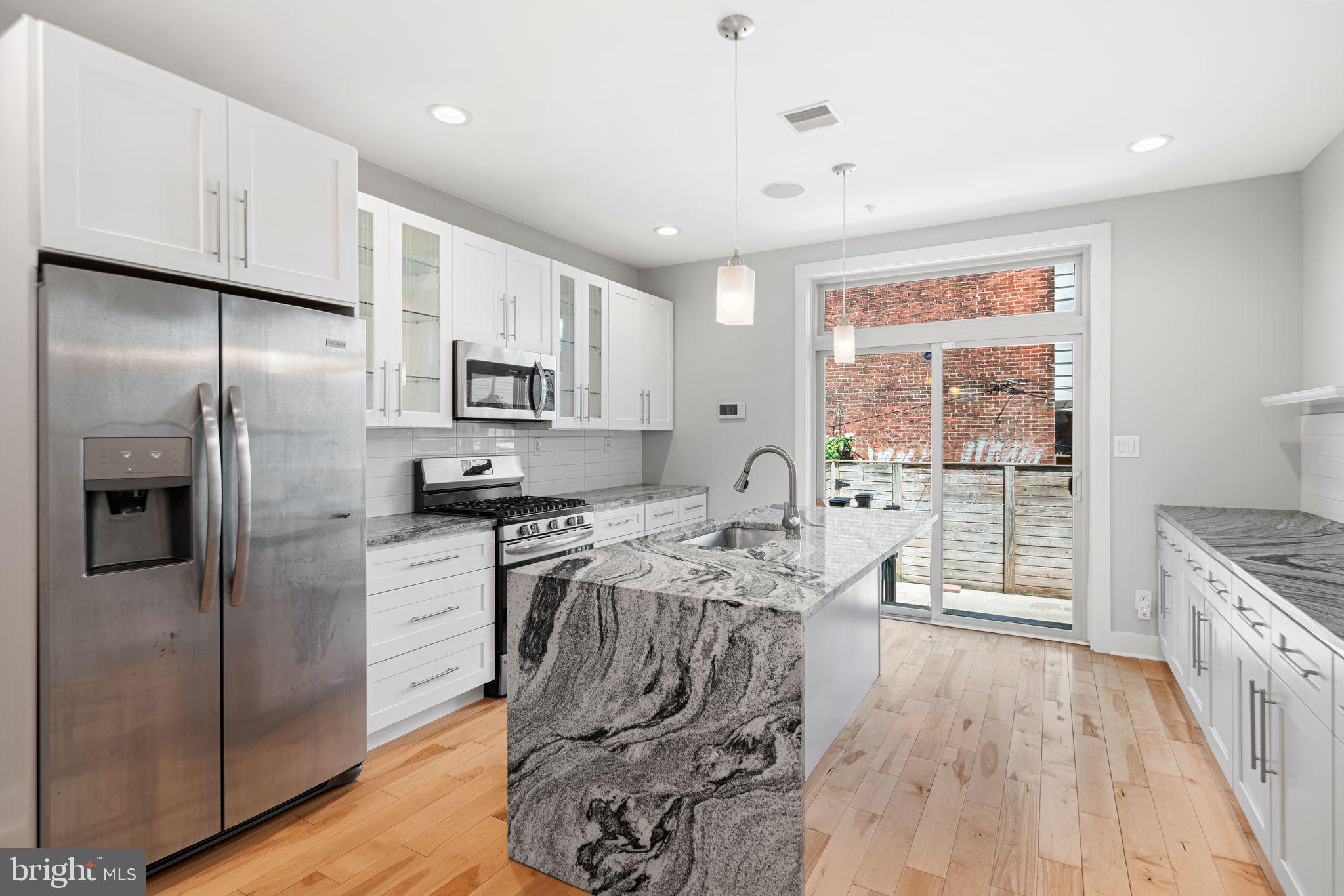 Welcome to this beautiful newer construction home with an oversized 15x63 lot in Point Breeze! Quality craftsmanship and high-end finishes make this new construction home stand out from the rest. An open floor plan welcomes you with soaring 9ft ceilings, gorgeous birch hardwood floors, a gas fireplace with floor-to-ceiling porcelain tile cladding, and fully wired speakers that run throughout the home set the tone for the attention to detail at every turn. The stunning kitchen's black-and-white swirled granite countertops and waterfall island with pendant lights add a touch of glam to the classic white Shaker-style J&K cabinetry, subway tile backsplash and stainless-steel appliances. Sliding doors at the rear provide tons of natural light and easy access to the large patio for grilling or entertaining. As you head upstairs, you'll find two large bedrooms that rival each other in size, both with deep closet space, oversized windows, and high ceilings. On the 2nd floor is also a stylish hall bath with a floating white vanity and tiled floor and shower, as well as a laundry closet. Head to the 3rd floor to find a massive master suite equipped with 2 large closets and a huge en-suite bathroom featuring a double vanity, a marble walk-in shower with 2 shower heads, and a soaking tub. In the hallway you'll find a convenient half bathroom, as well as a wet bar with sink and mini fridge, perfect for entertaining guests and eliminating trips up and down the stairs. In the basement is an additional living space (that could be converted to a large 4th bedroom), and a full bathroom with walk-in shower. This home is mere minutes from Point Breeze favorites, both old and new, in addition to plenty of options nearby to enjoy community green space at Lanier Park or Wharton Square Playground. Several years left on the 10-year tax abatement! Come see this beauty today!