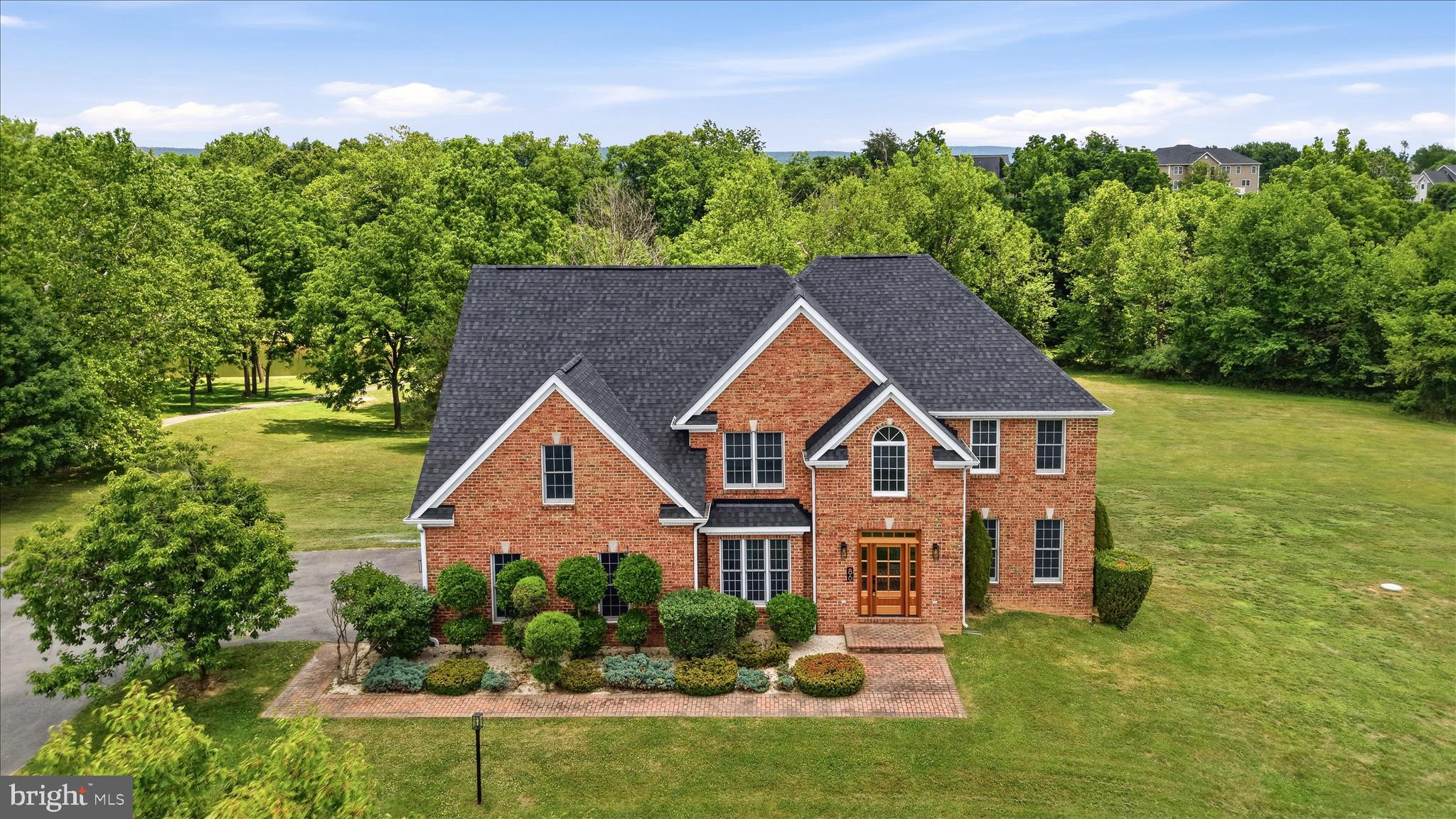 Set on the largest lot in Eastland, this completely renovated home spans almost 3 private acres backing to Evitts Run with lake views, the kind of scale and setting that are increasingly hard to find. A classic brick facade opens to a two-story foyer with hardwood floors that run throughout the main level. A formal living room, ideal as a home office, complements the elegant double-door dining room, while a main-level bedroom and full bath offer exceptional versatility for guests, multigenerational living, or everyday convenience. The heart of the home is the new eat-in kitchen, featuring brand-new Cafe' stainless-steel appliances, quartz countertops, an oversized island, and a striking backsplash. Just off the kitchen, a spacious family room anchored by an electric fireplace creates the perfect gathering space, while the breakfast area opens to an expansive new private deck overlooking the lake and Evitts Run, creating a peaceful backdrop for outdoor dining, entertaining, or simply enjoying the view. Upstairs, three more bedrooms and a bedroom-level laundry room with a new front-load washer and dryer surround the primary suite, which features a custom tile shower, modern soaking tub, separate vanities, and a large walk-in closet. For added comfort and privacy, the upper level includes a princess suite with a private attached bath, along with two spacious secondary bedrooms connected by a Jack-and-Jill bath. The walkout basement is ready to finish and is already improved with a full bath featuring a walk-in shower. Located in the sought-after Eastland community, residents enjoy access to a recreation trail and scenic walking paths leading to the lake and Evitts Run, enhancing the neighborhood's natural appeal. Add a new architectural shingle roof, a two-car garage, a wooded backdrop, and quick access to Route 340 toward Winchester, Leesburg, and Northern Virginia, and you have a move-in-ready home that lives large in Charles Town.