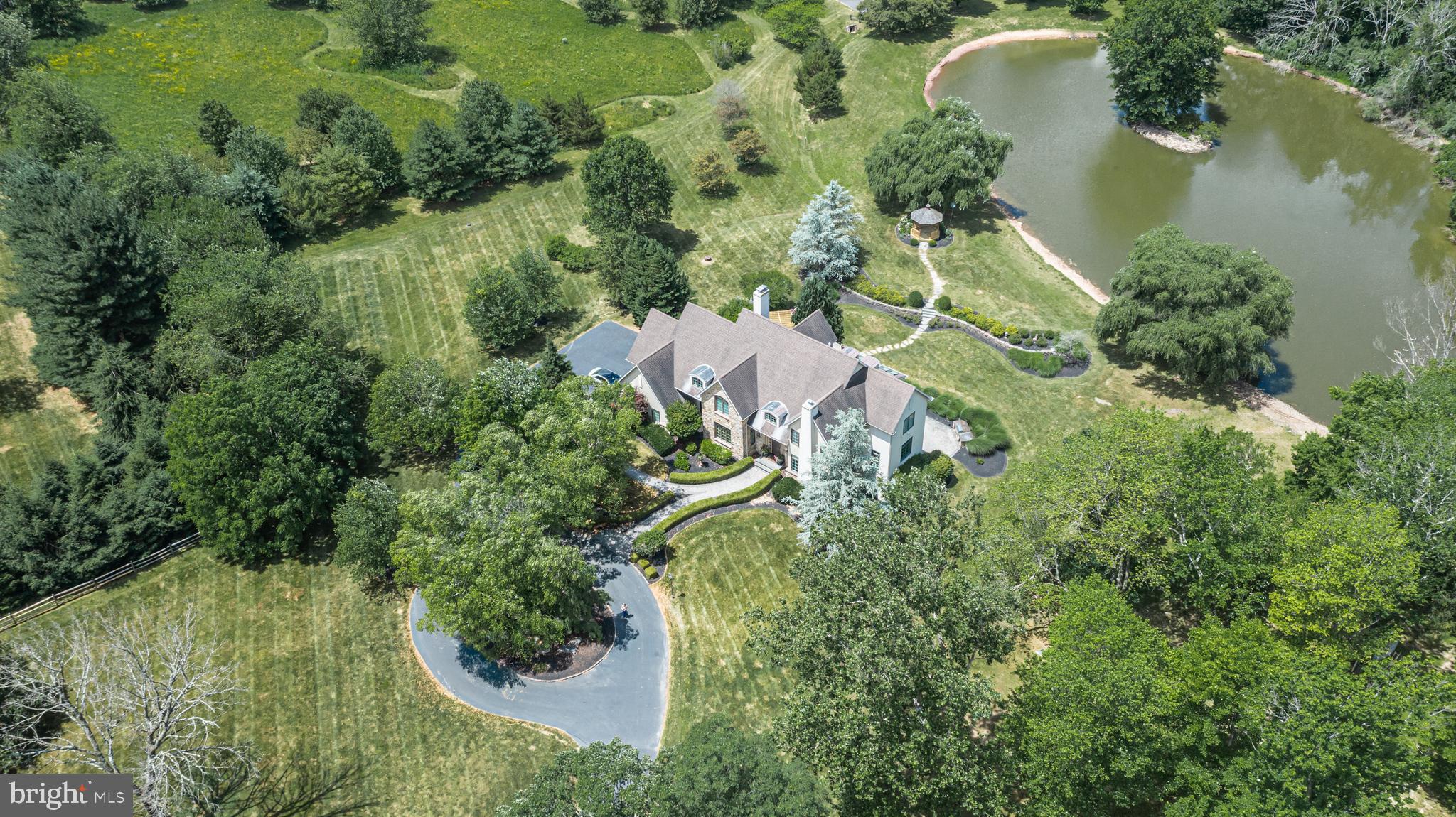 An exquisite country estate offering picturesque views from every room and incredible space while maintaining timeless details and classic charm. Set amidst 10+ acres in the heart of Buckingham Township with your own private pond, this stunning Zaveta custom home welcomes you at every turn with quality craftsmanship, premium amenities and a magnificent landscape. Beautifully updated and distinct, the entry is memorable with its tree lined drive leading to a circular courtyard which overlooks the manicured grounds. Classic moldings adorn the formal living space with gas fireplace which flows effortlessly into the elegant formal dining room. The centerpiece of the home is the designer gourmet kitchen and certainly a cook's dream with a remarkable oversized island, quartz counters and a suite of high-end stainless-steel appliances including a paneled Sub-Zero refrigerator and 6 Burner Wolf range. Take in the serene pond views during meals in the sun-filled dining nook. Adjacent is the spacious gathering room, with its stone floor-to-ceiling fireplace which welcomes any size gathering. A wall of windows with French doors leads to the magnificent terrace, perfect for alfresco dining with amazing views at every turn. Rounding out the main level is a private study, spacious laundry room and stylish half bath. Upstairs, the primary suite is in a world of its own with two massive walk-in closets outfitted with custom organizers, a luxurious smokey gray and white marble bath that includes an oversized walk-in shower, freestanding soaking tub and separate water closet. One bedroom is ensuite and the remaining two secondary bedrooms share a jack and jill bath. Descend to the incredible walk out lower level, sure to be the home to many celebrations, which offers multiple living spaces, a full bath, a game room with full bar area, and opens to a delightful paver patio complete with built-in grill on one side and an enclosed wood-lined ceiling patio on the other. Elegant details such as arched doorways, transoms, skylights, extensive moldings, hardwood floors and beautifully designed outdoor living spaces including a pergola covered deck and gazebo by the pond will welcome you at every turn. Enjoy roaming the lush, landscaped grounds connected by blue stone walkways, standing on the dock or paddling in the pond to your very own island. With a 3-car garage, generator and located in award-winning Central Bucks School District, this exceptional estate offers unparalleled luxury and tranquility just minutes from Doylestown and New Hope for dining, nightlife and shopping and is conveniently situated for access to Philadelphia, New Jersey and New York. Schedule your private tour today.